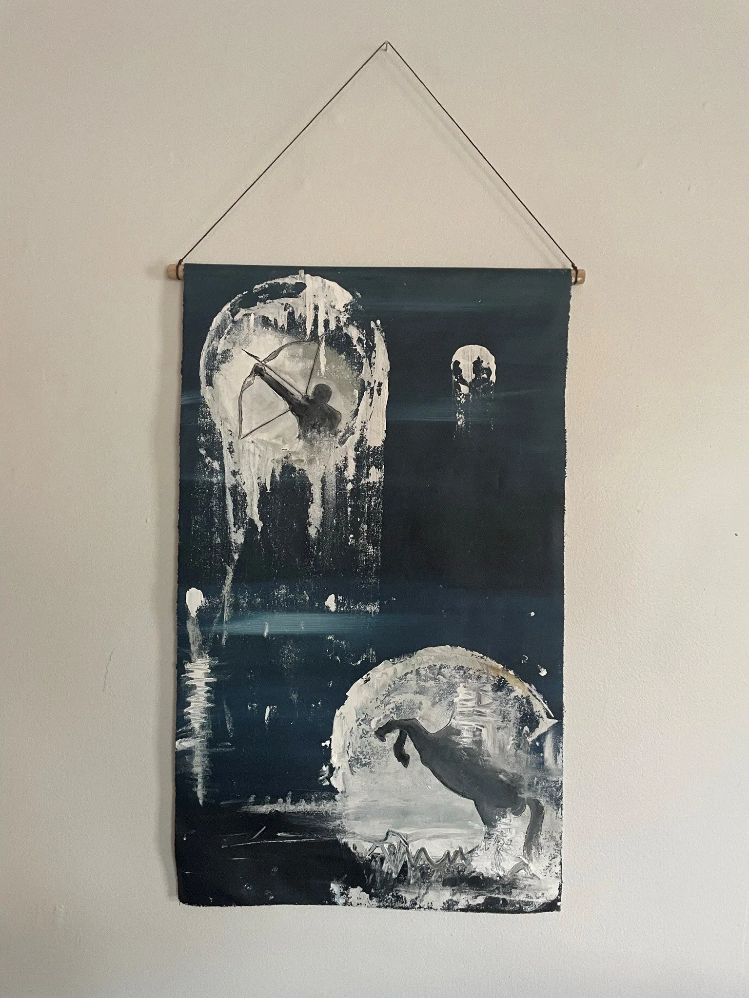 A black and white painting depicting a large moon in the background, with a wolf howling in front of it on a mountain or hill. The painting has a textured and abstract style.