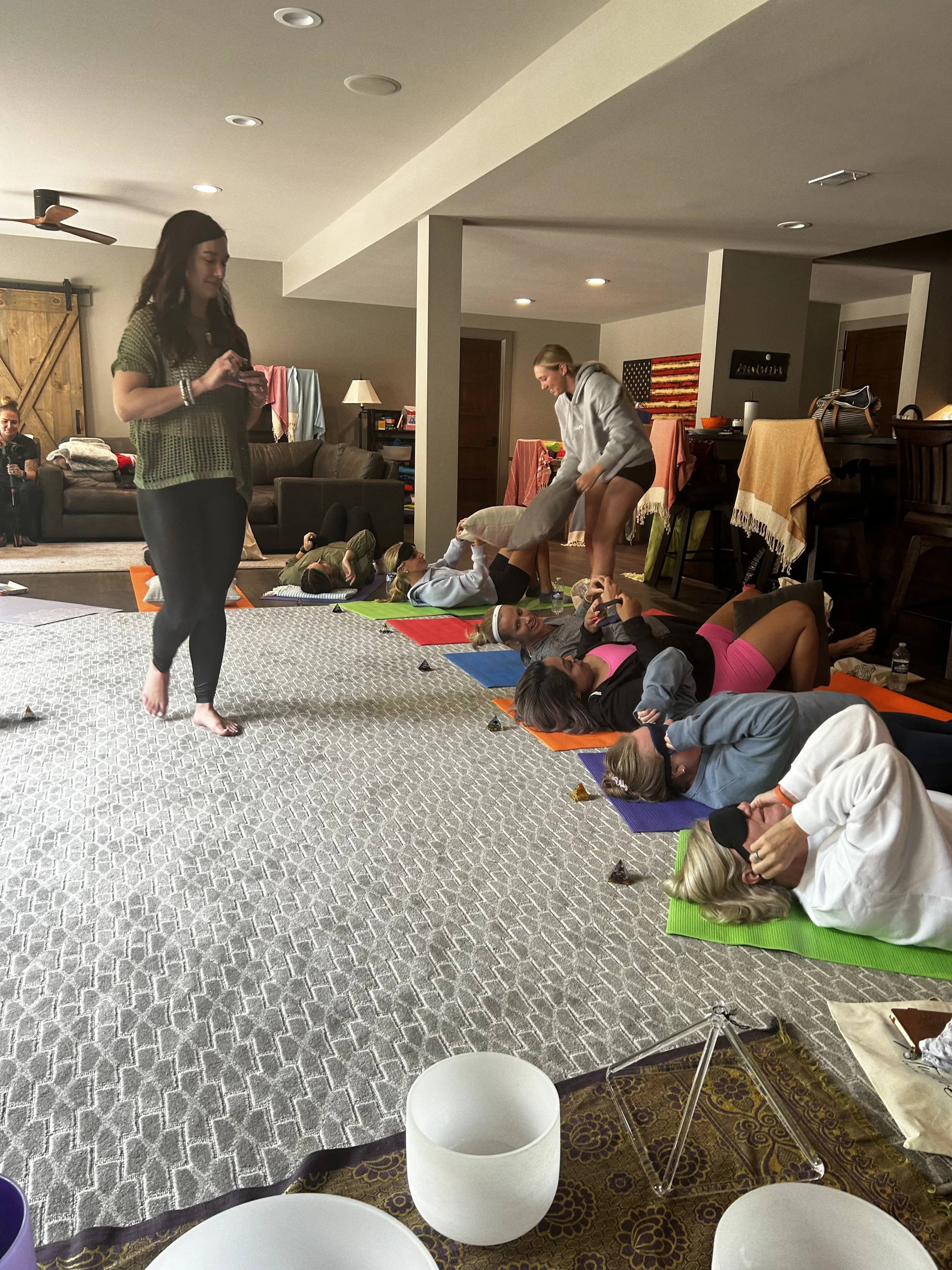 Group of women participating in a yoga or meditation session on colorful mats in a cozy living room.
