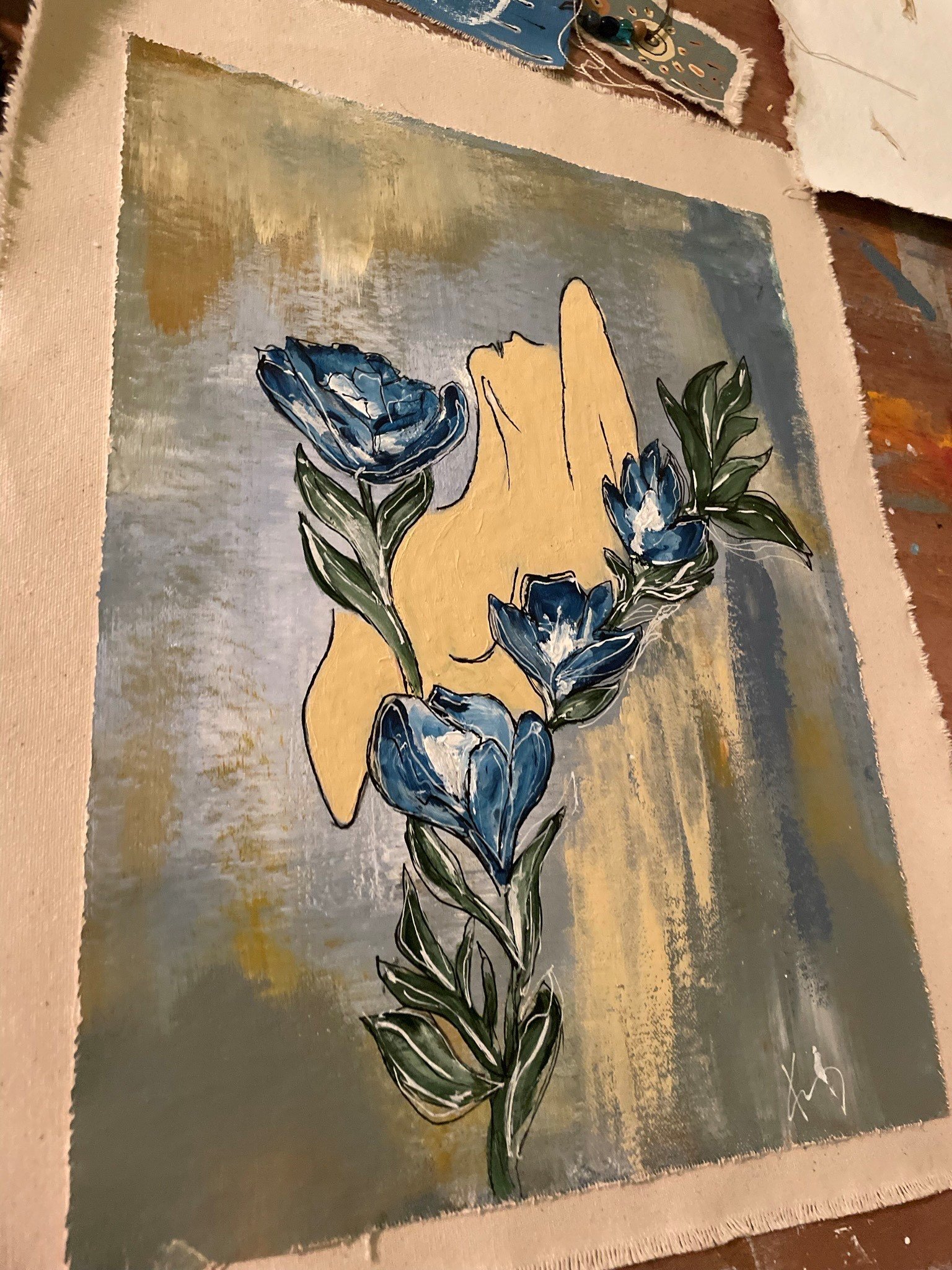 A painting of a yellow hand holding a branch with blue flowers and green leaves, set against a textured background with shades of gold, gray, and green.