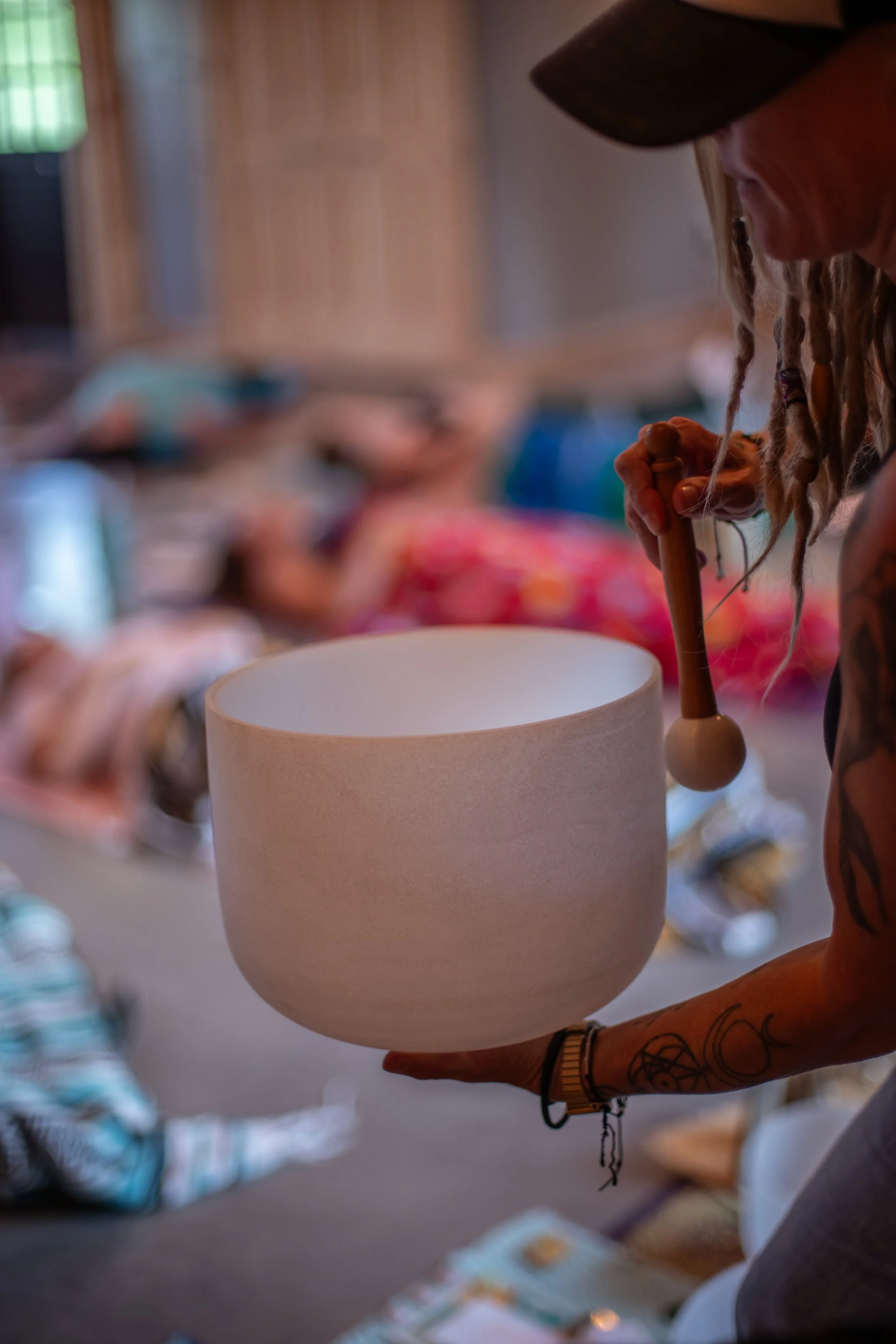 A person holding a white lampshade in one hand with a blurred background of various items on a table.