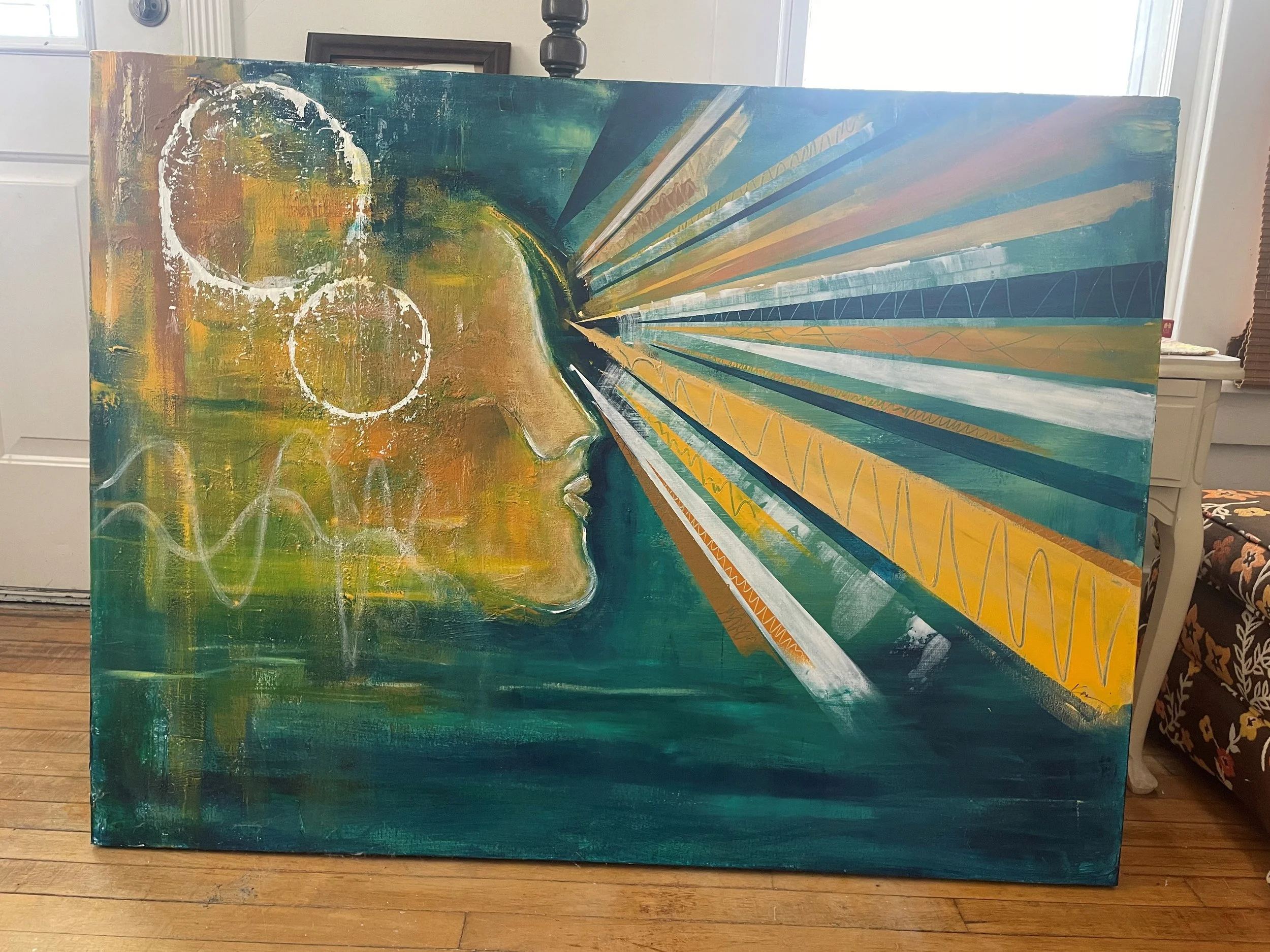 Abstract painting on canvas showing a profile of a person's face with closed eyes, rendered in earthy tones, combined with vibrant geometric lines and rays extending outward in various colors, mounted on an easel in a room.