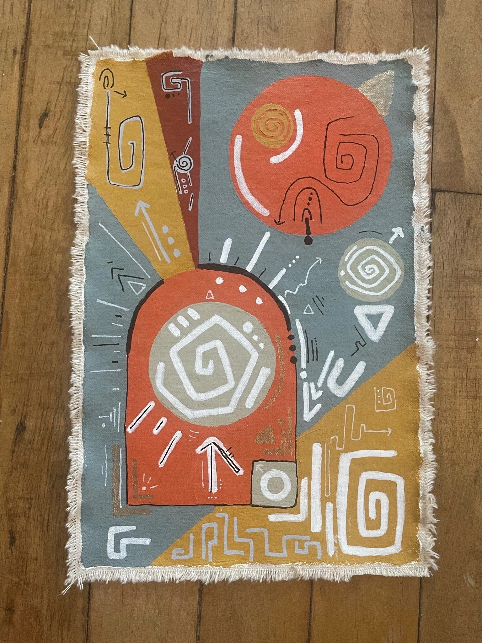 Abstract artwork on a small fabric piece with colorful shapes, spiral patterns, and lines in shades of red, orange, blue, beige, and white.