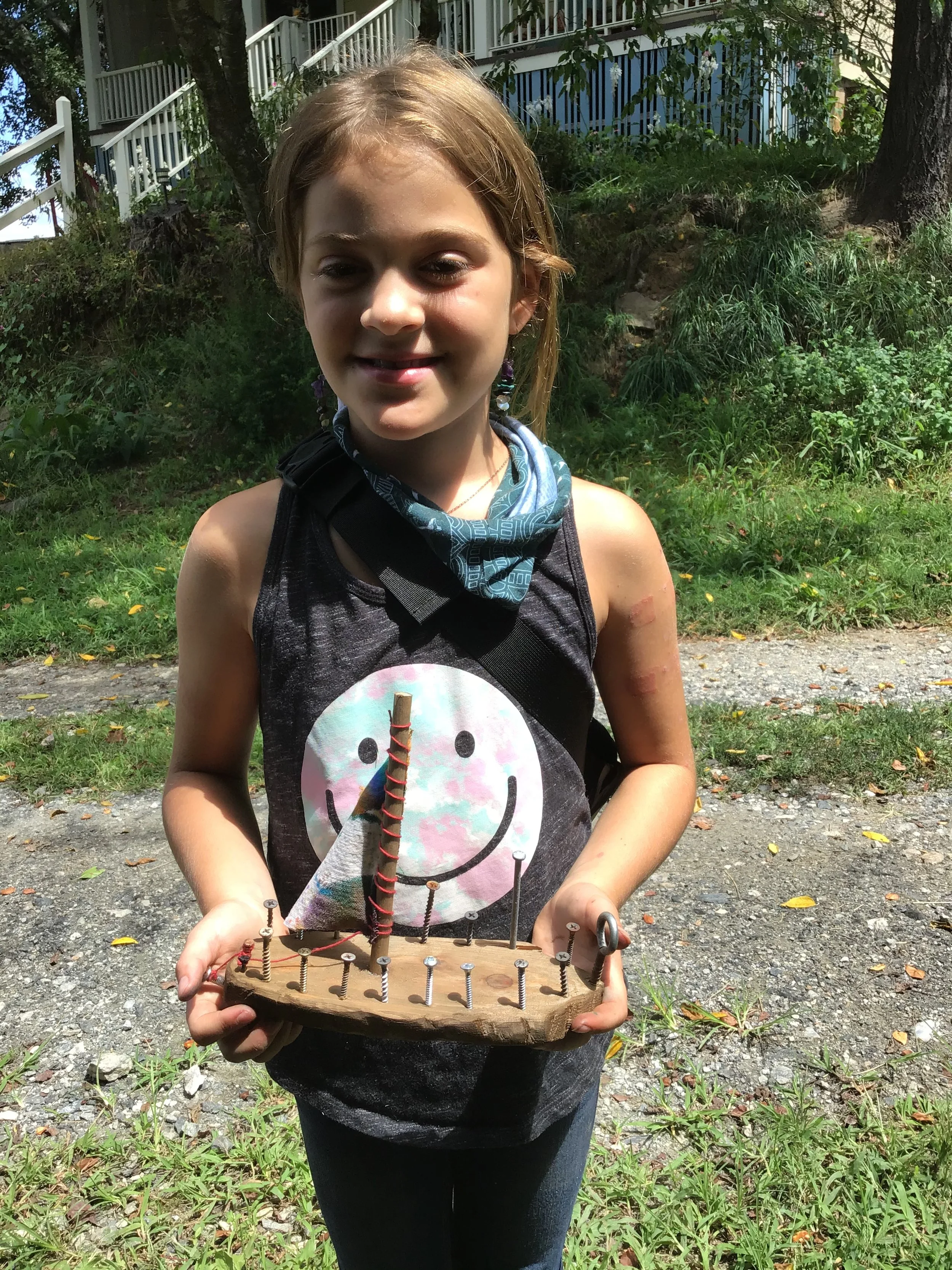 Student holding hand carved boat. 