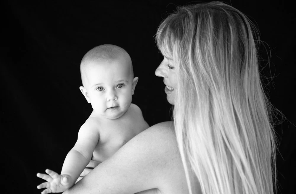 A woman holding a baby with a black background.
