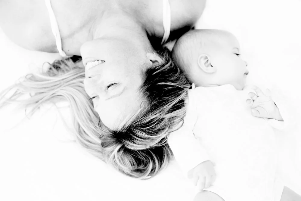 Black and white photo of a woman and a baby sleeping side by side, lying on their backs with heads close together.