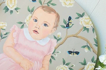 custom painted portrait of a 1 year old child in a vintage pink baby dress. The background has golden color flowers and butterflies. 