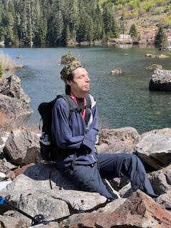 Basking in the warm sun, Tiye feels God's favor, knowing his prayers will be answered after one week—just in time to help him with this hike, and as he climbs the mountain, pushing his limits, he cherishes this fresh day granted by God's grace, knowi