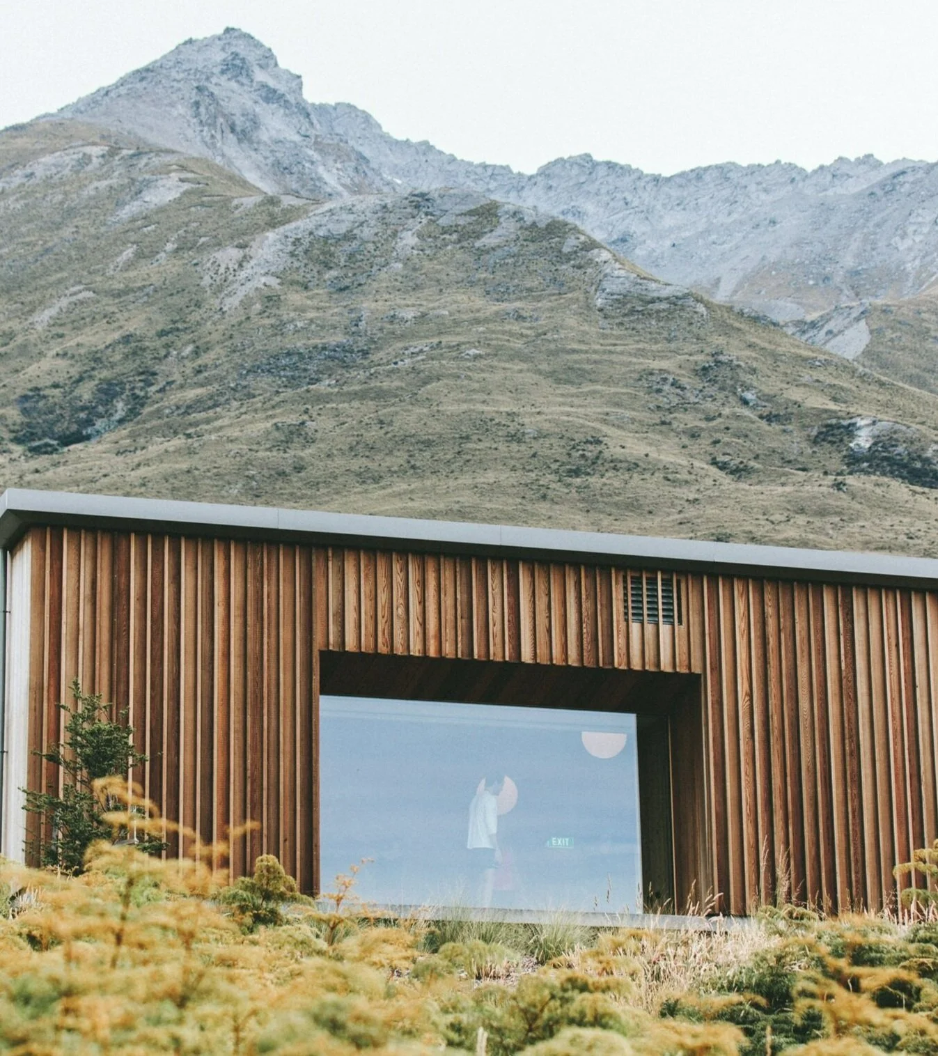 Modern wooden building with large window in mountainous landscape