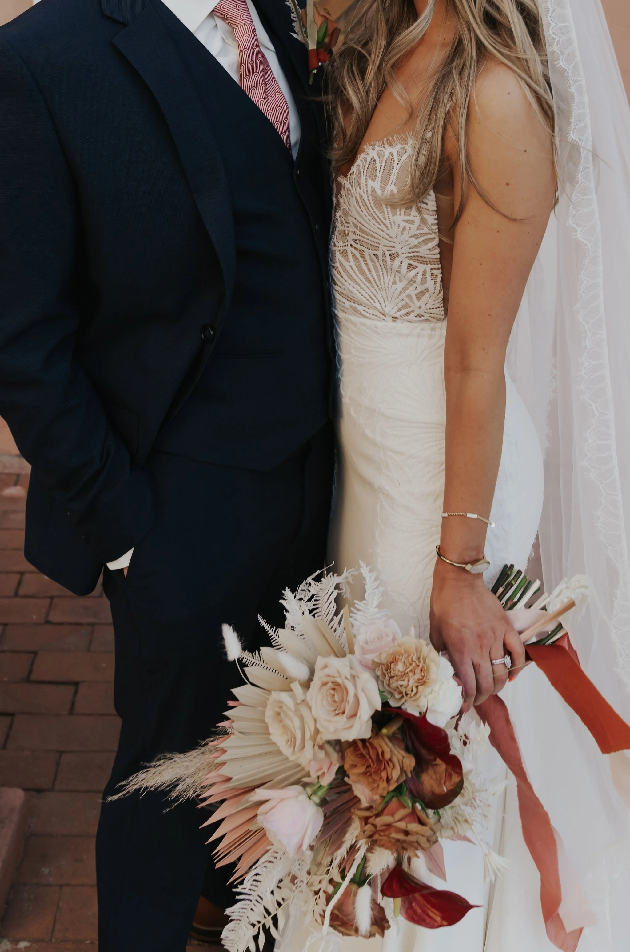 Bride in white dress holding bouquet, standing next to groom in dark suit.