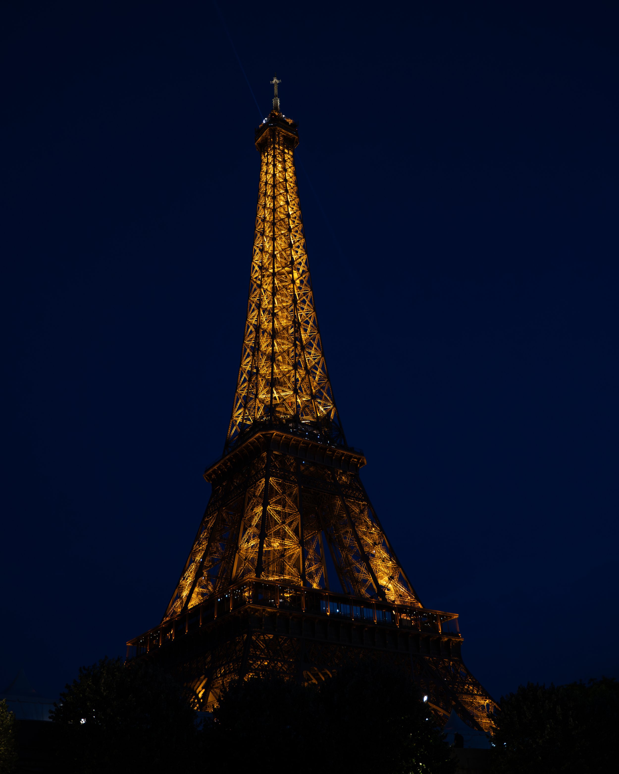 Night view of the illuminated Eiffel Tower against a dark sky in Paris.