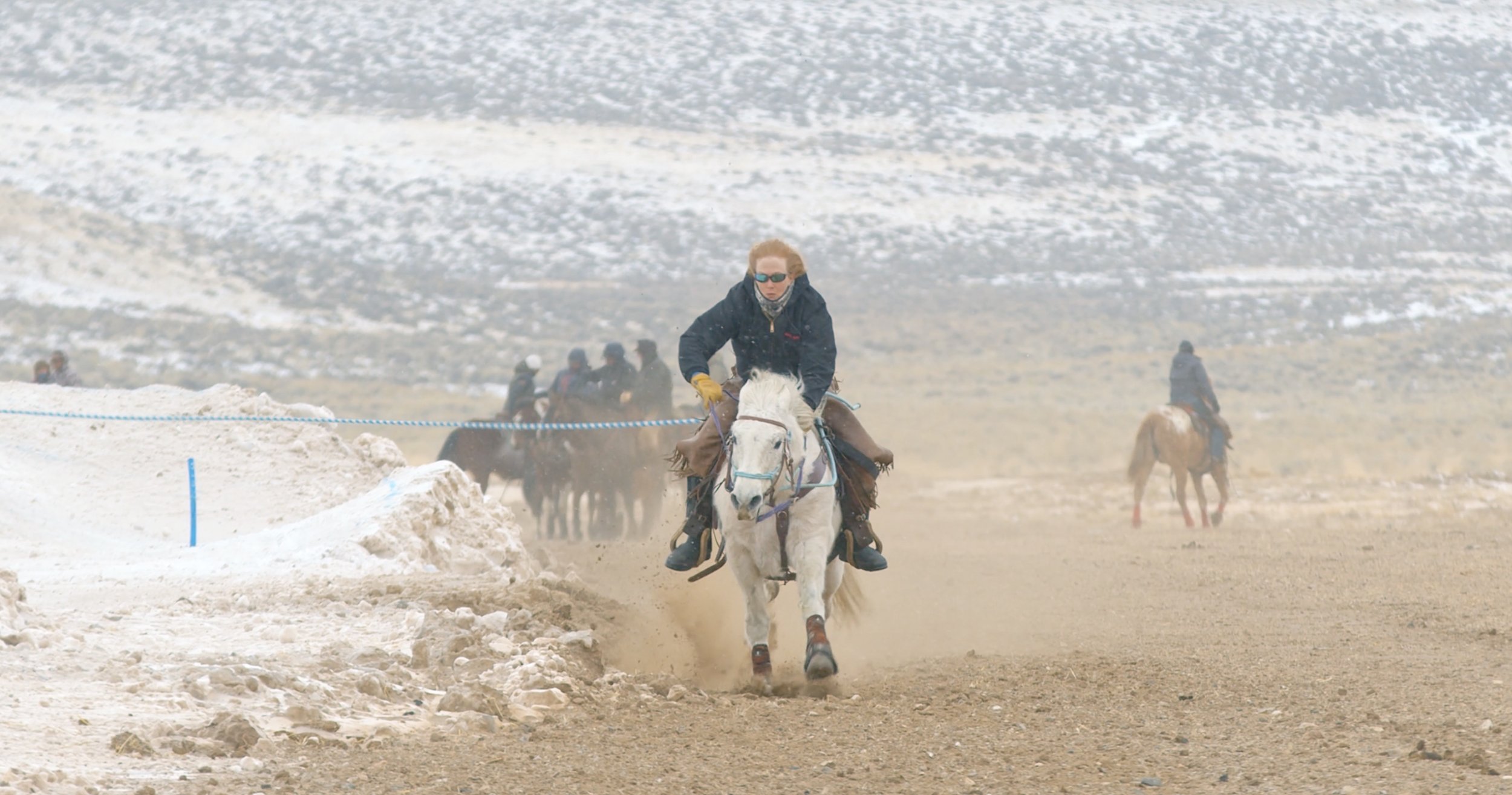 Person riding a white horse on a snowy outdoor trail