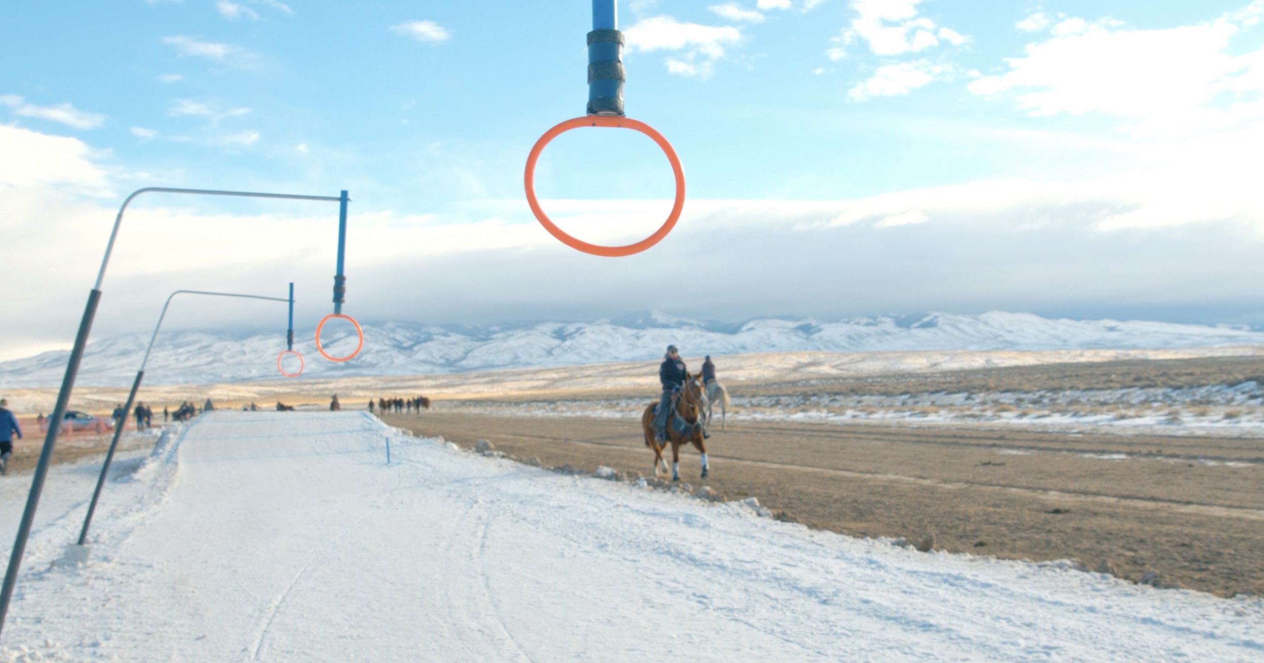 Snow-covered landscape with orange hoops and a person on horseback.