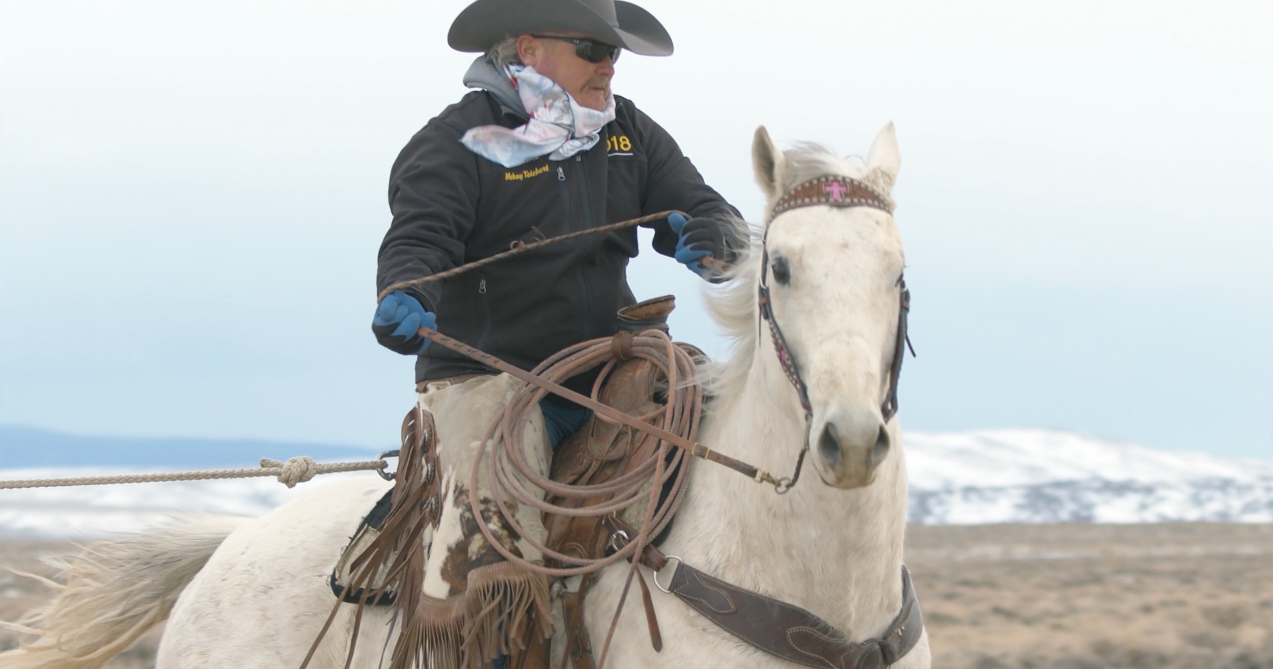 Cowboy riding a white horse in a snowy landscape