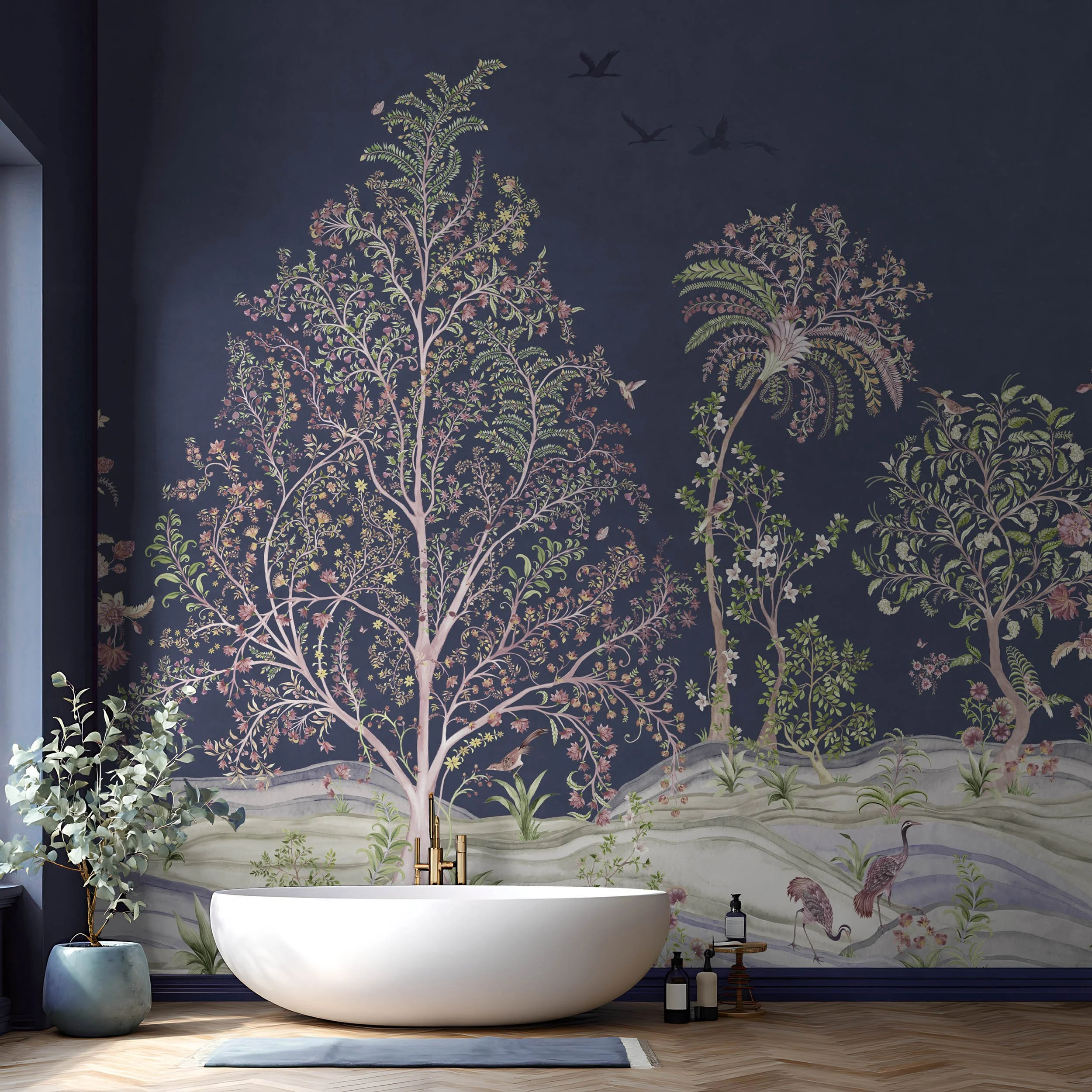 Storybook Garden Midnight Blue botanical wallpaper mural in a bathroom, featuring hand-painted trees, palms, birds and a whimsical landscape behind a freestanding bath.