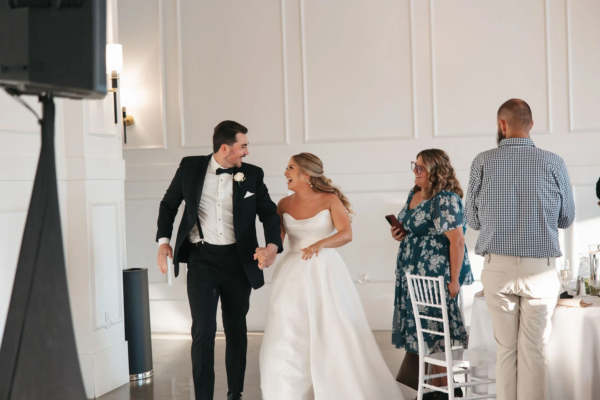 Bride and groom looking at each other smiling while running into wedding reception with guests standing and watching