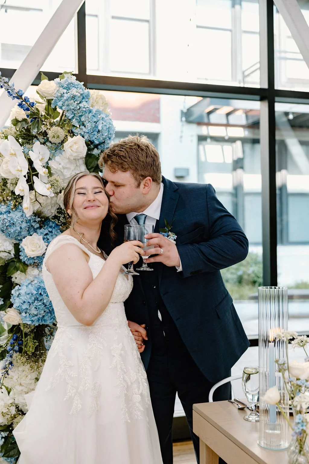 Chicago couple cheersing glasses with groom kissing bride's cheek at Greenhouse Loft