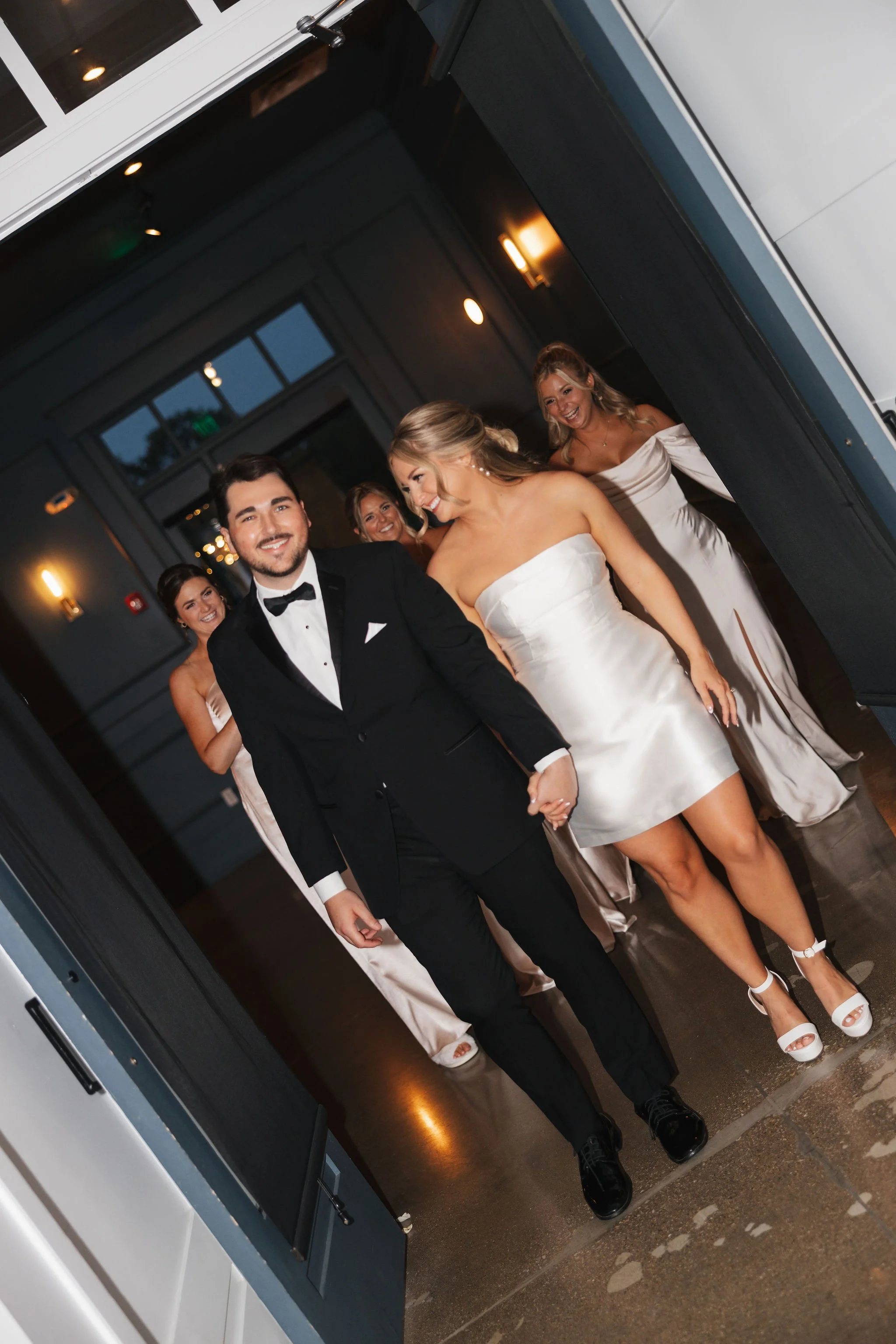 Bride and groom walking to reception with bridesmaids joining