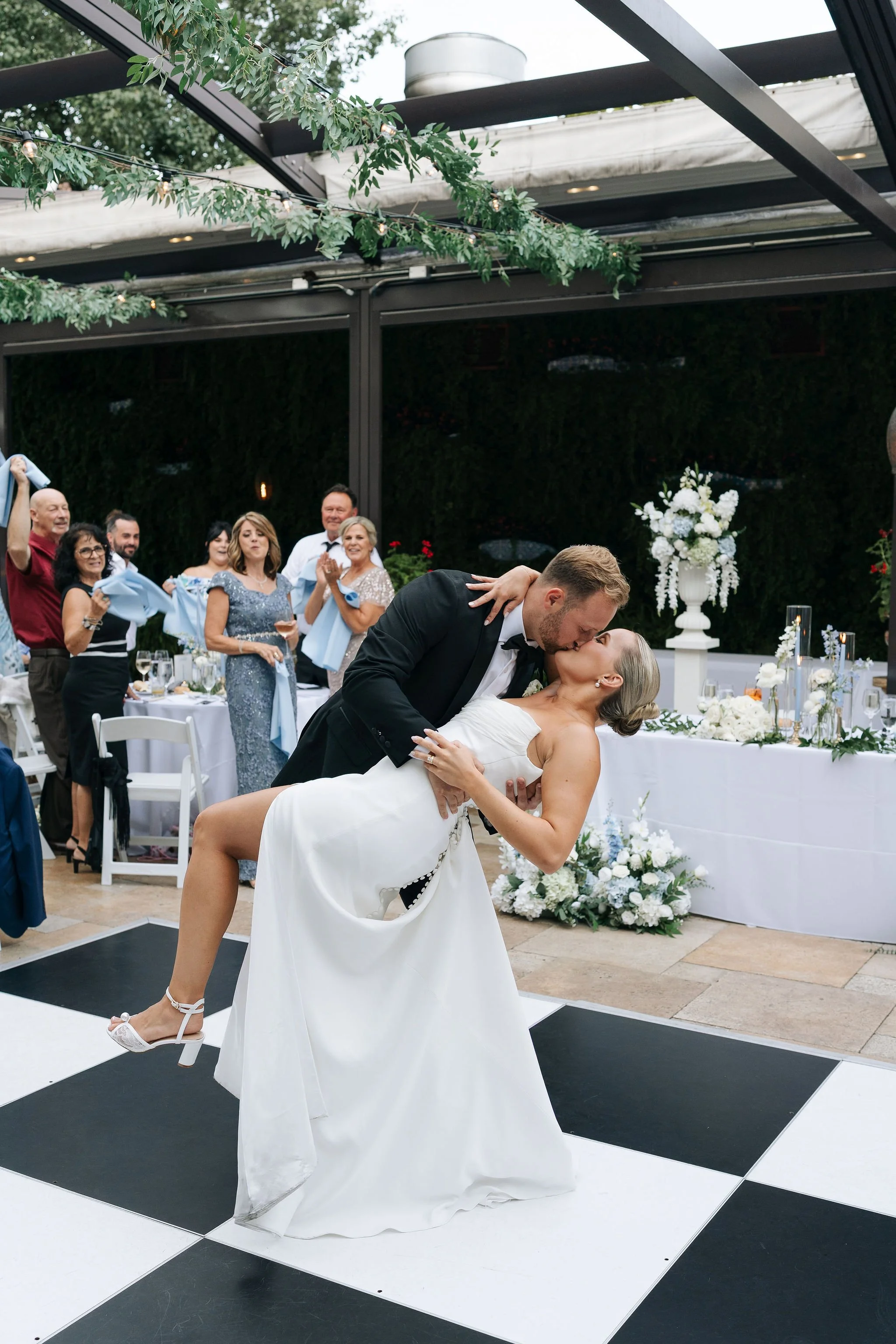 Groom dipping bride with a kiss on the black and white dance floor for grand entrance into wedding reception