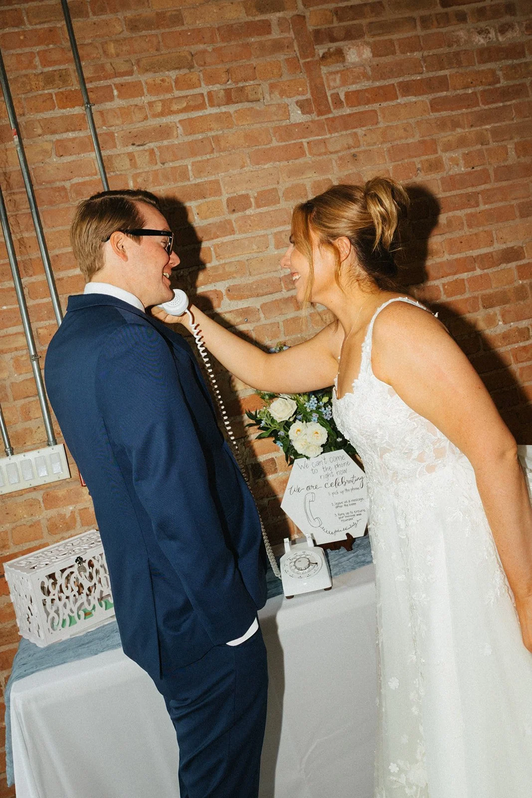 Bride holding up telephone for groom using audio wedding guest book at reception at Floating World Gallery in Chicago