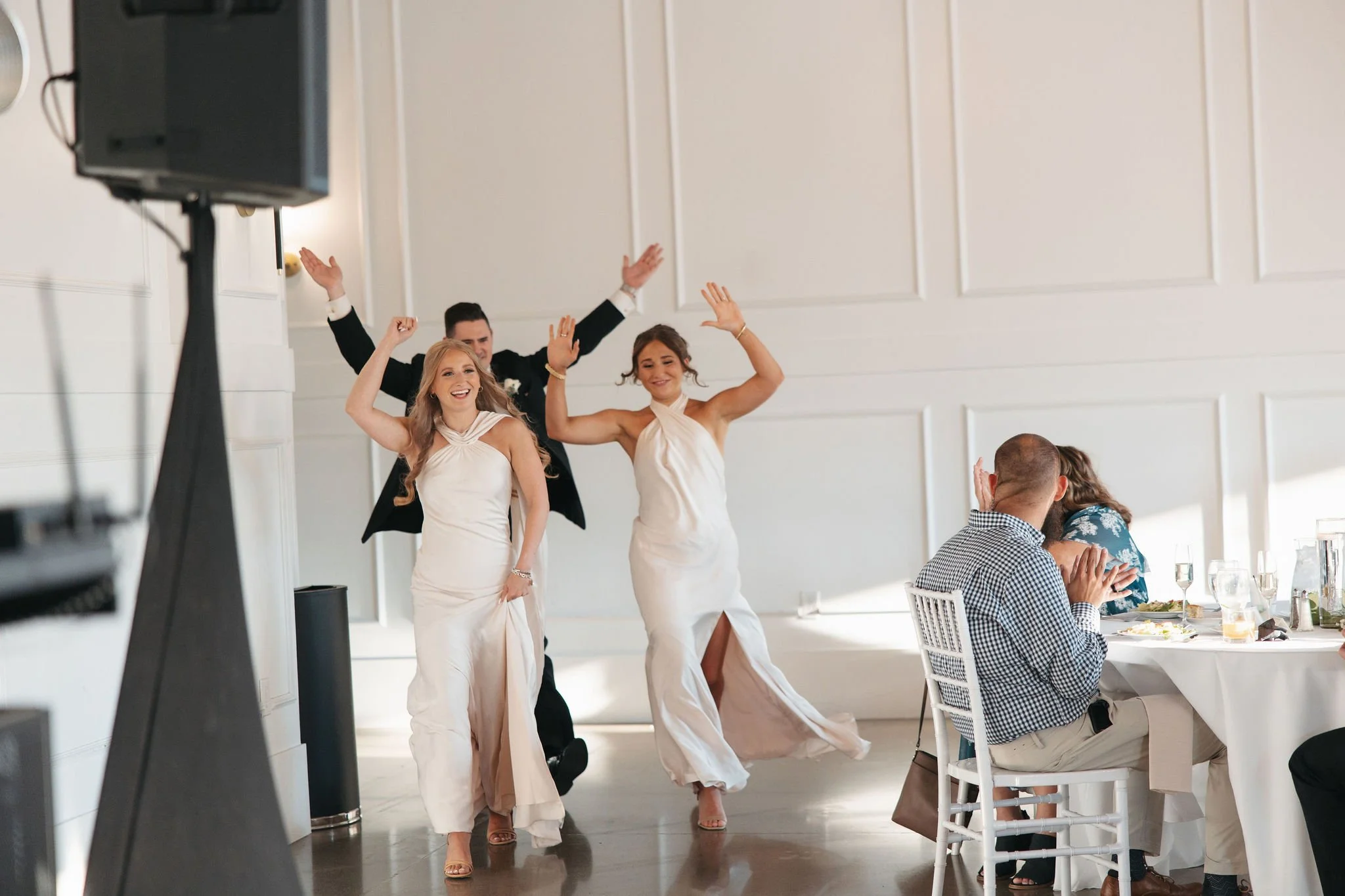 Two bridesmaids and groomsmen getting guests pumped during wedding grand entrance