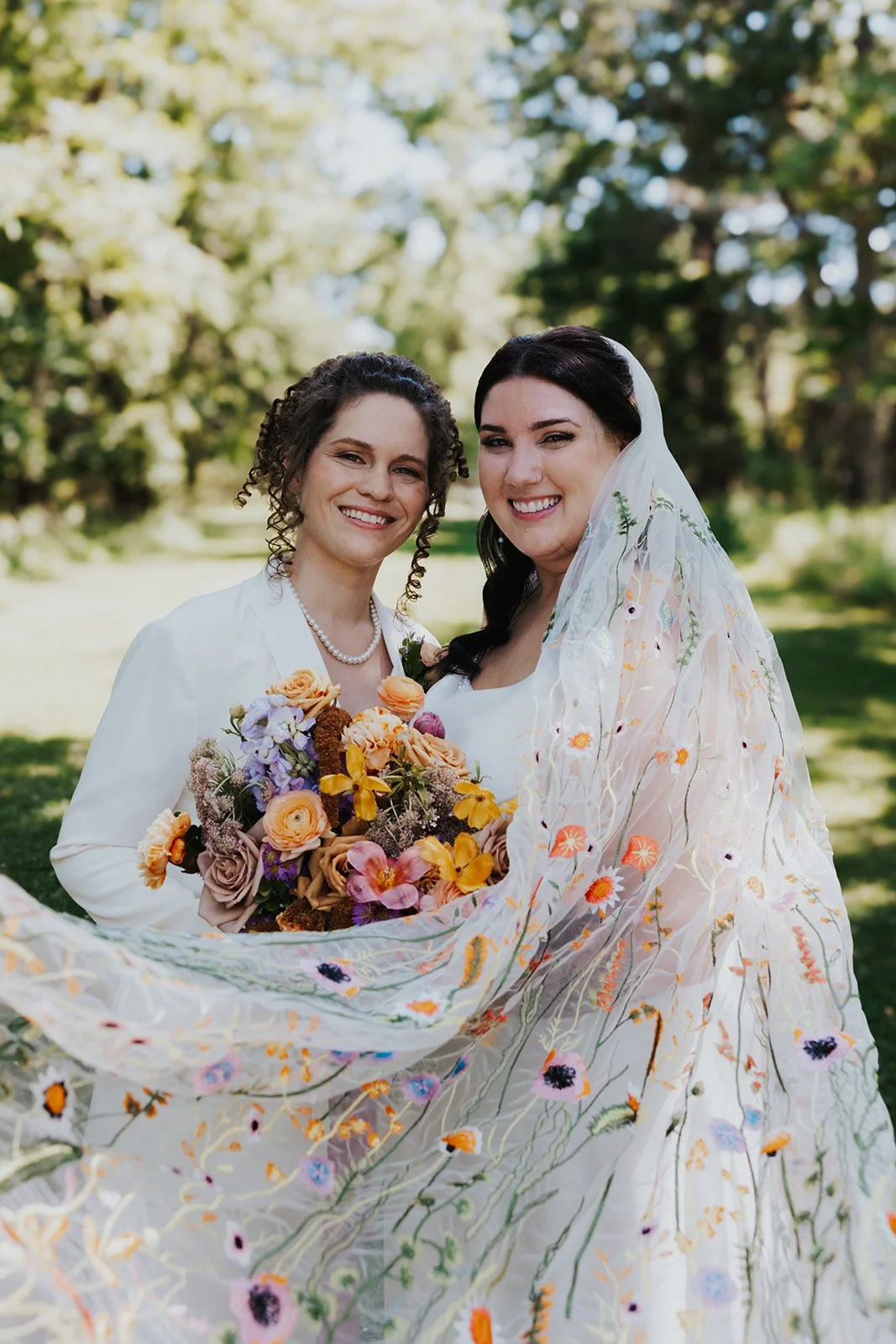 Formal photos of brides looking at camera and smiling with embroidered veil flowing