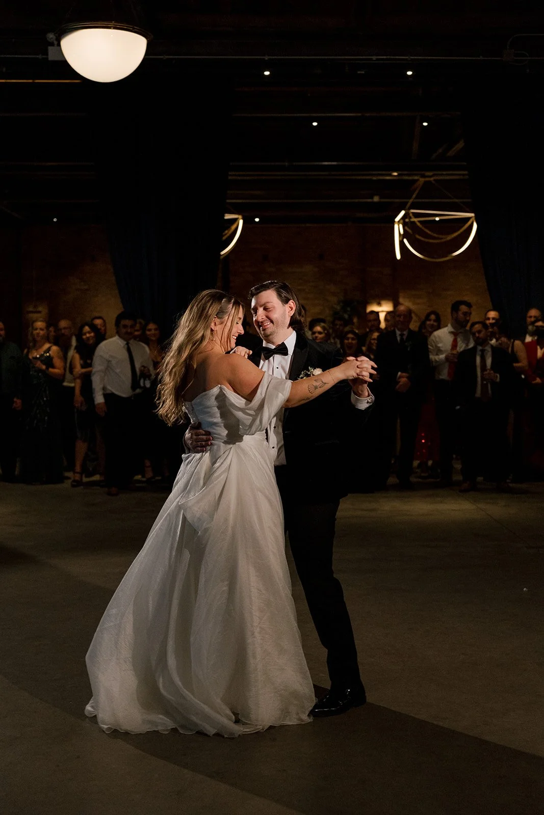 Bride and groom dancing on dance floor during wedding reception and wedding guests watching