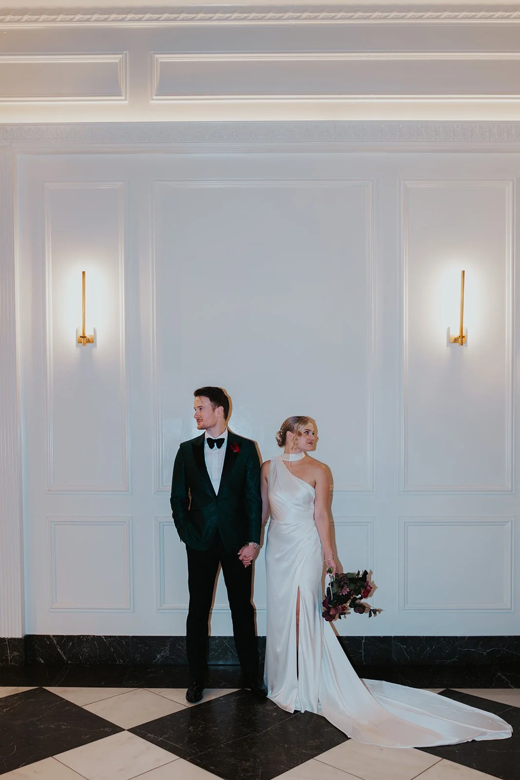 bride and groom standing next to each other looking separate ways flash photography with modern white background
