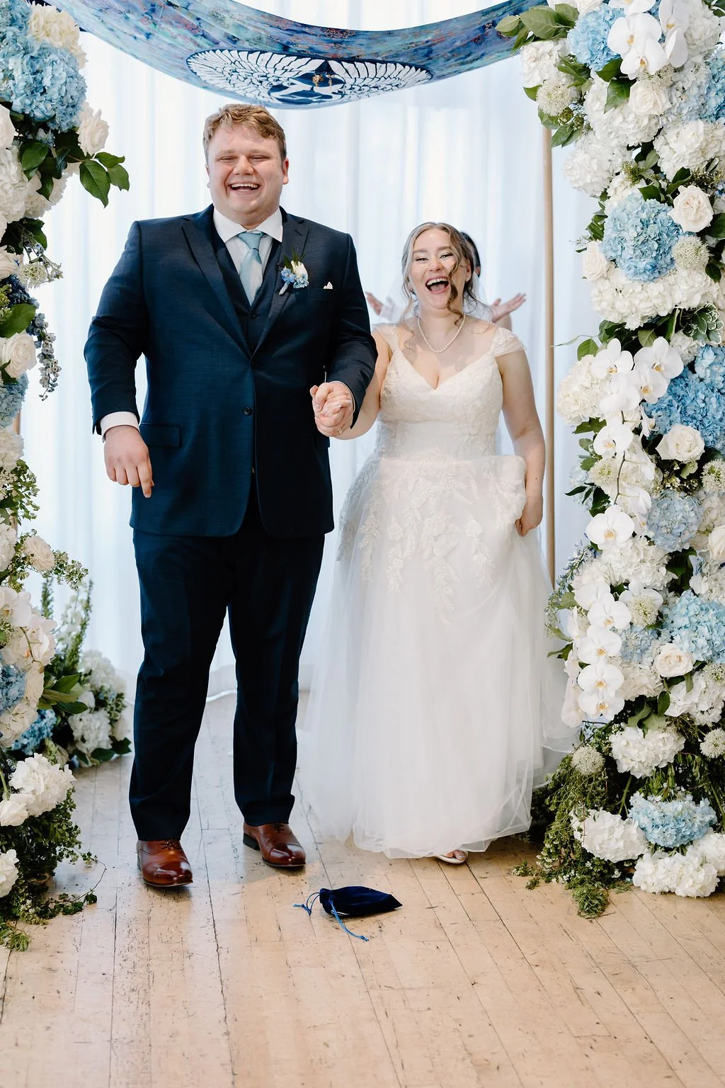 Mazeltov couple smiling and cheering under chuppah