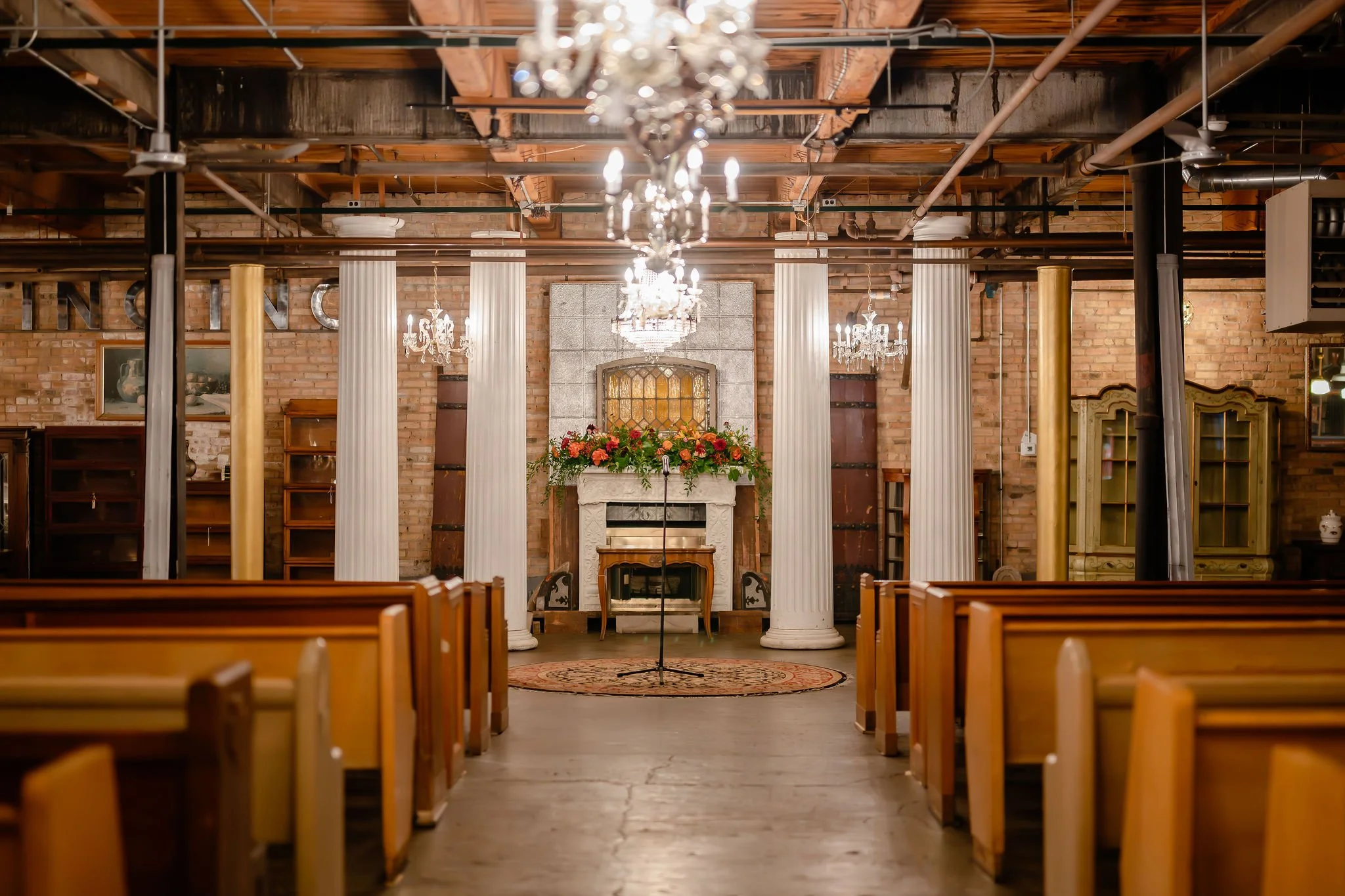 Church pews, Greek columns, antique chandeliers, and vintage rug at wedding ceremony altar