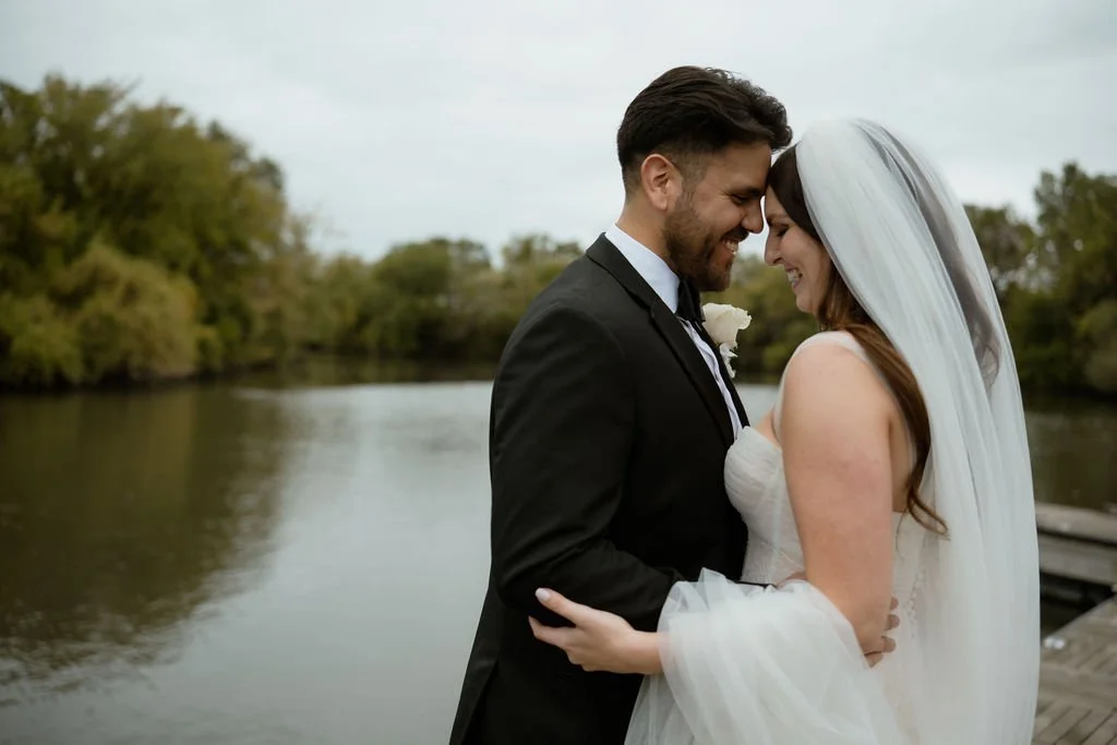 Bride and groom standing with foreheads touching and laughing with Chicago river as the background