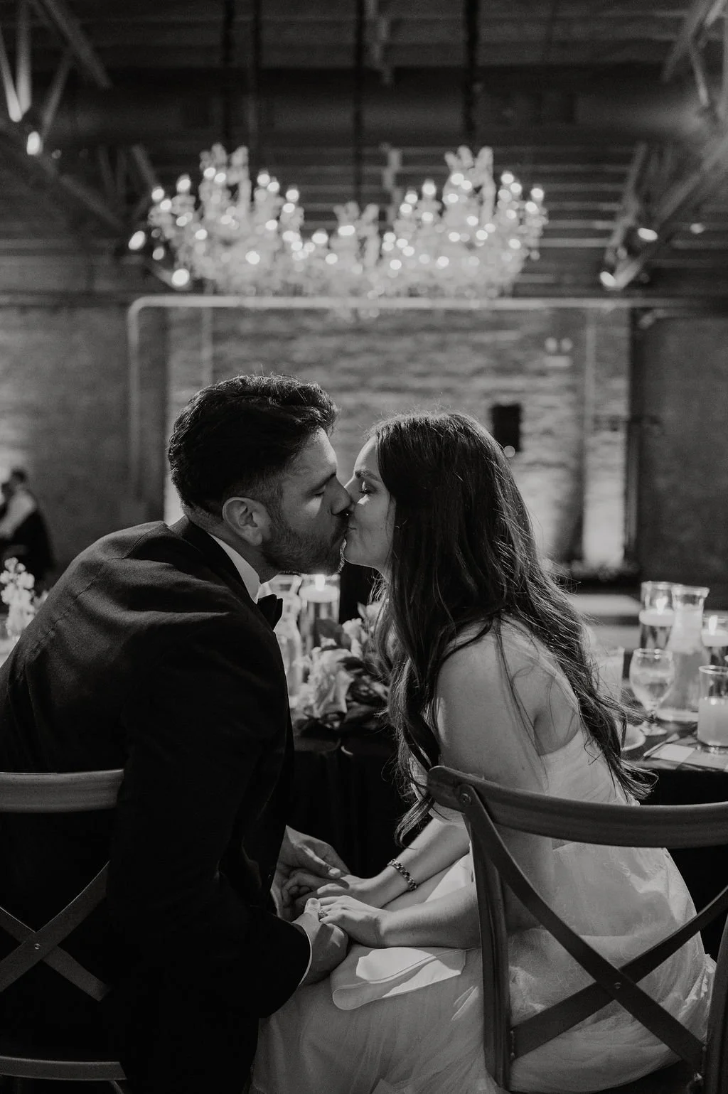 black and white photo of couple kissing at head table