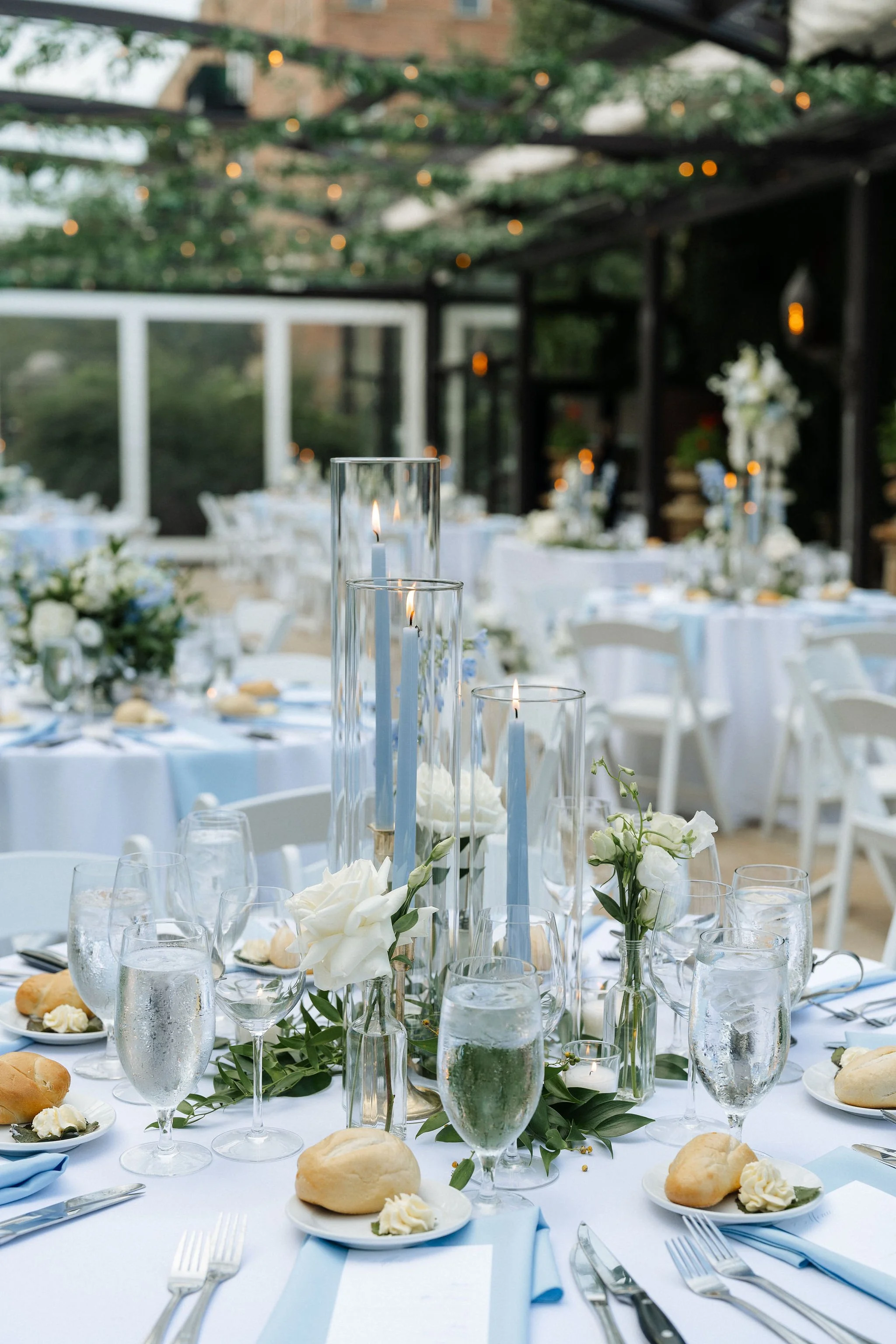 blue taper candles closeup of tablescape centerpiece with silverware and bread on the table for the dinner reception