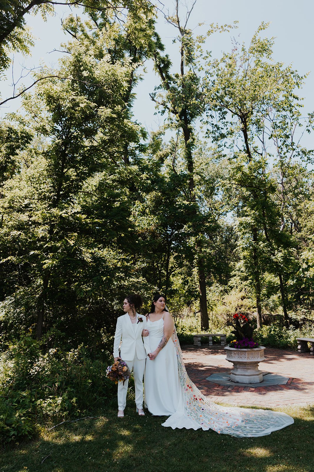 Two brides standing next to each other far away while looking in opposite directions serious