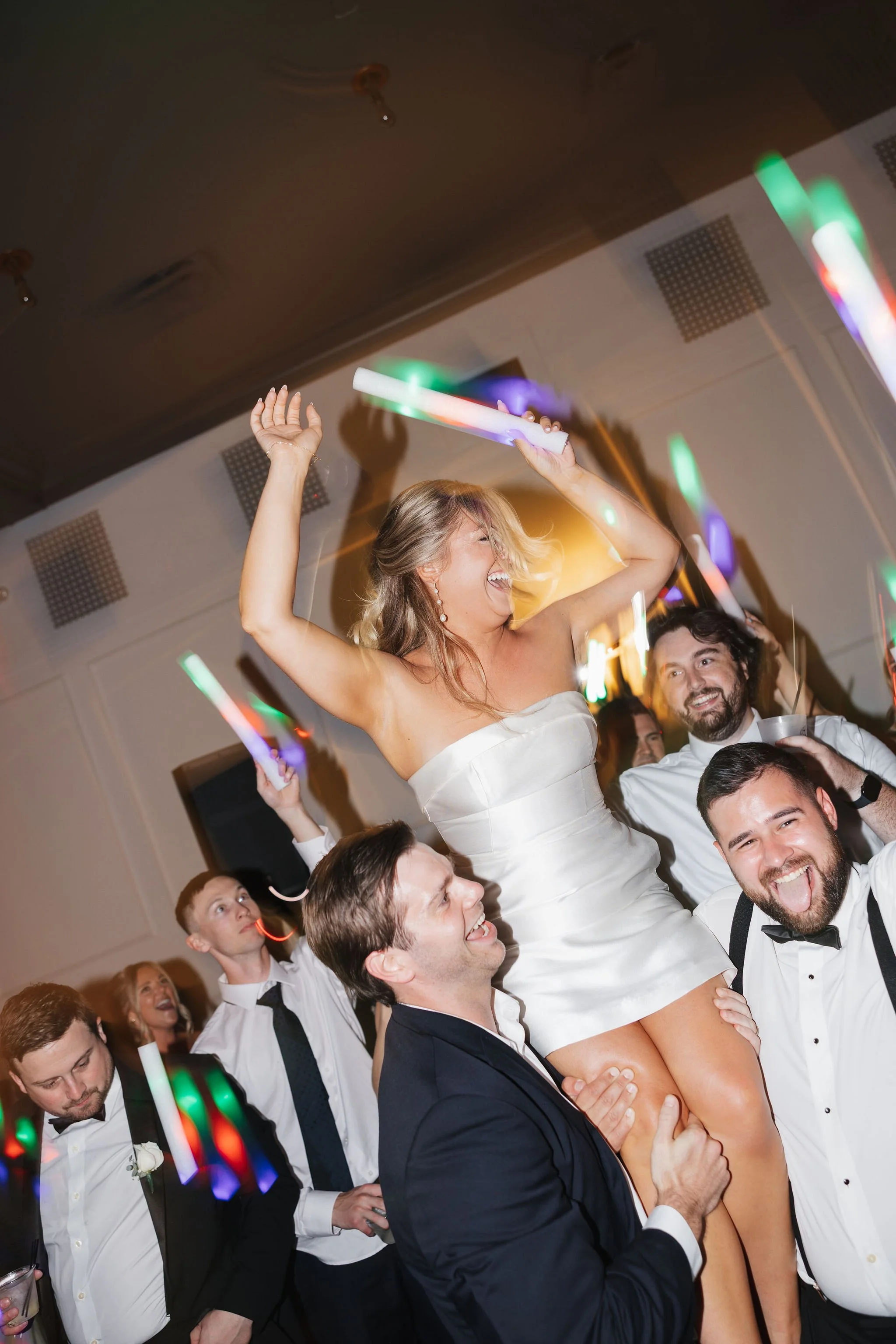 Bride lifted on two men's shoulders while cheering