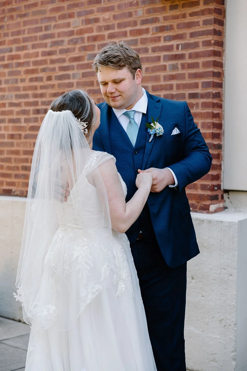 Groom looking at bride while holding her hand at first look