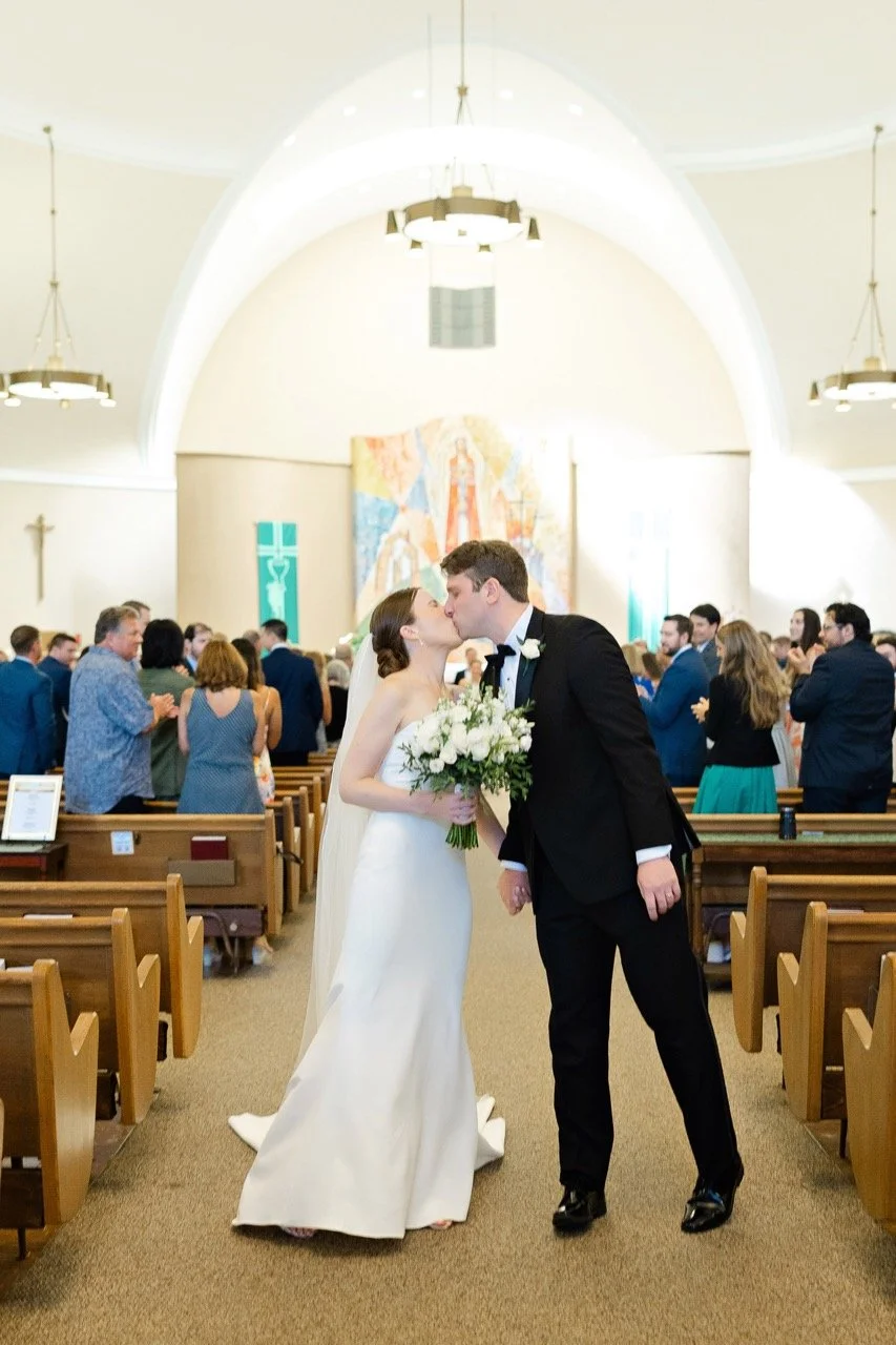 Bride and groom in aisle kissing at wedding ceremony recessional