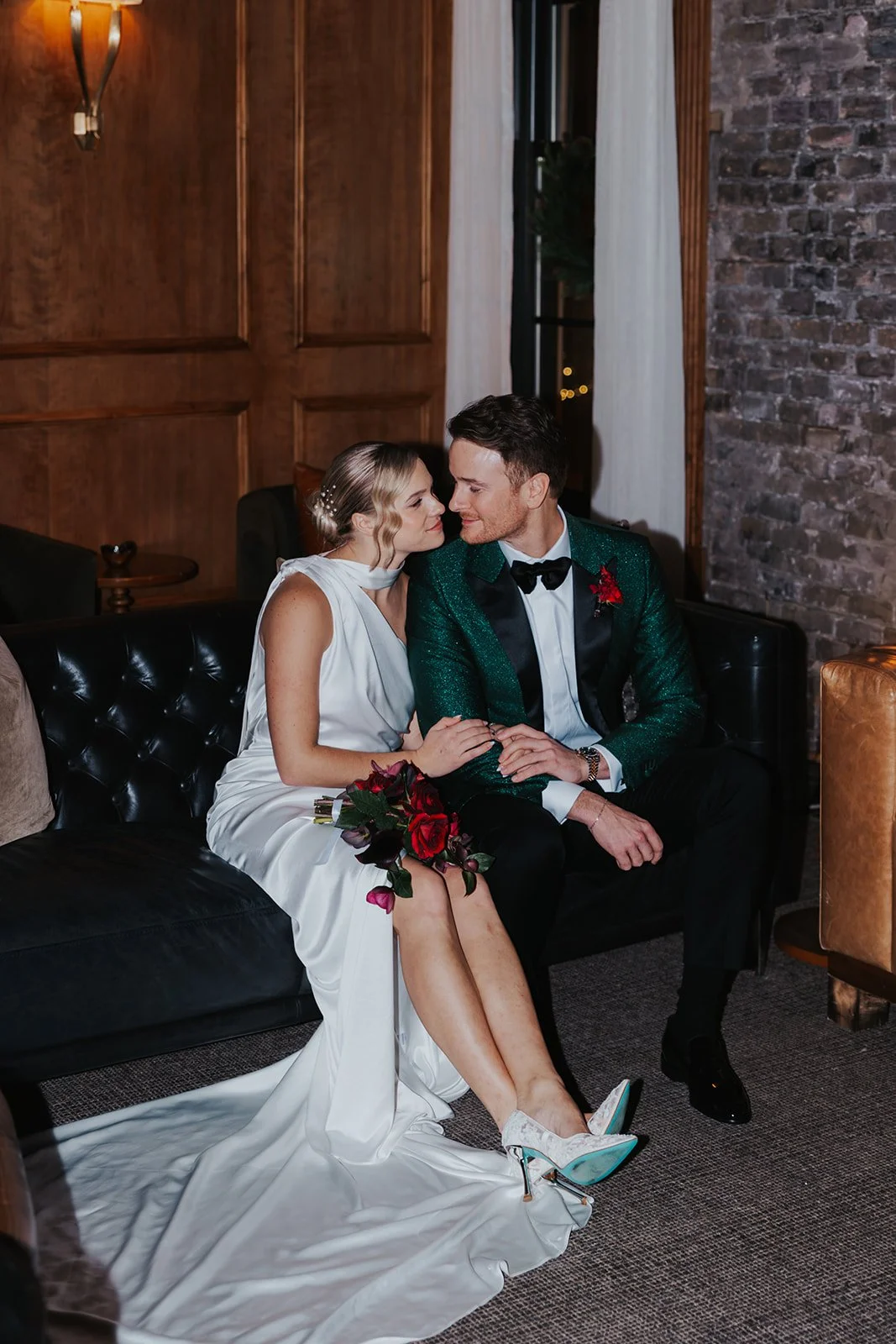 bride and groom sitting on lounge furniture for couple's portraits in Library at Salon 61 Events