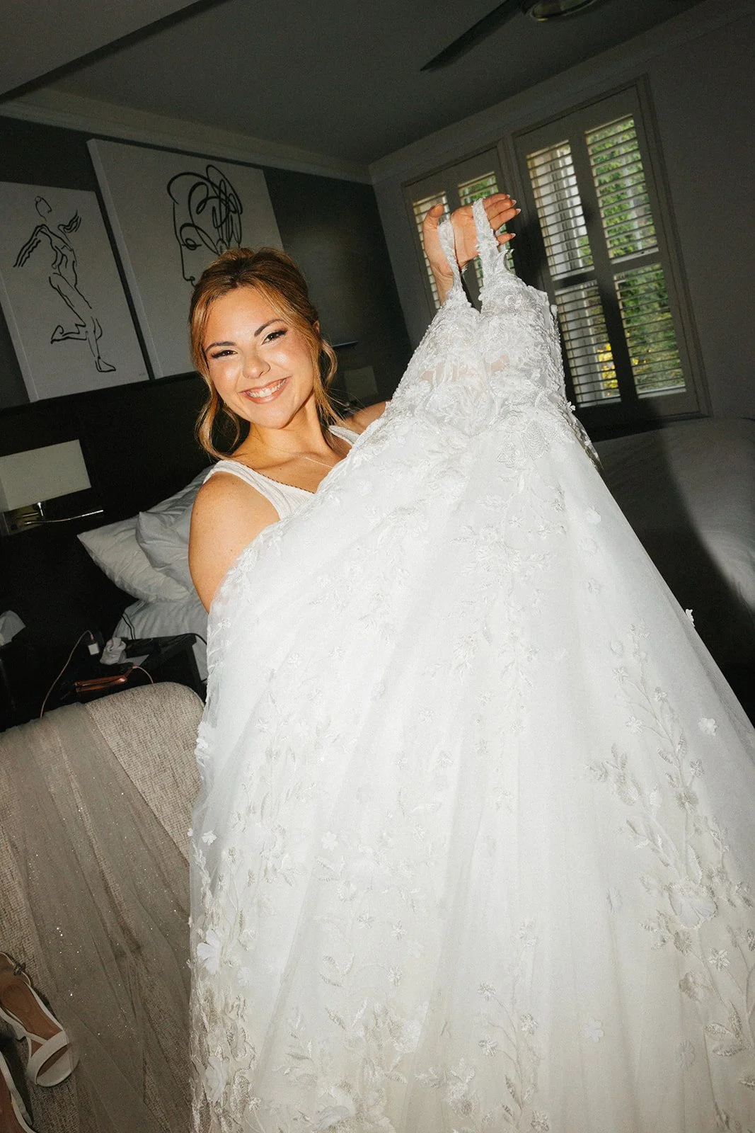 Bride holding her dress and smiling flash photo in getting ready space for Chicago wedding