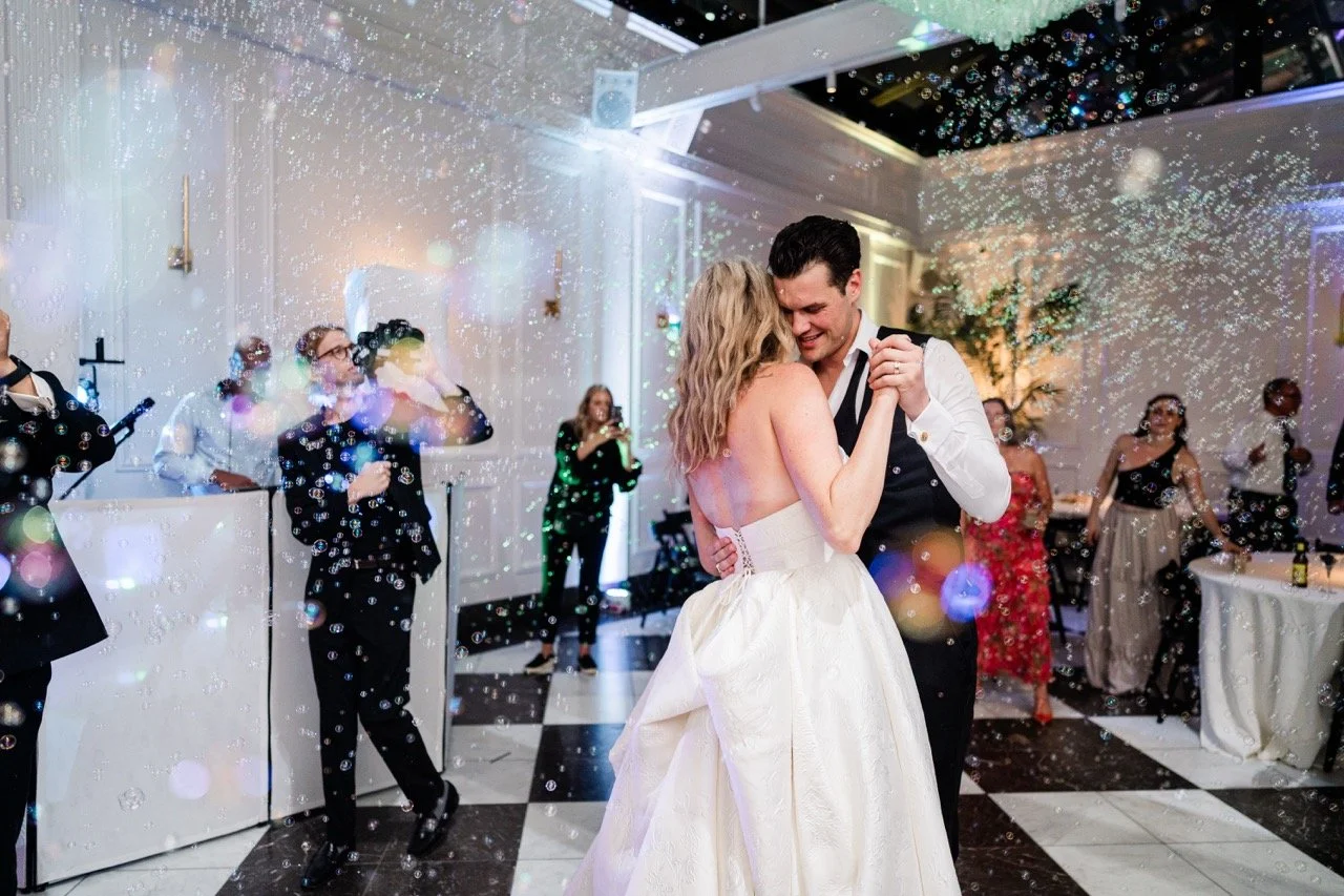 Groom smiling dancing with bride with bubbles blowing