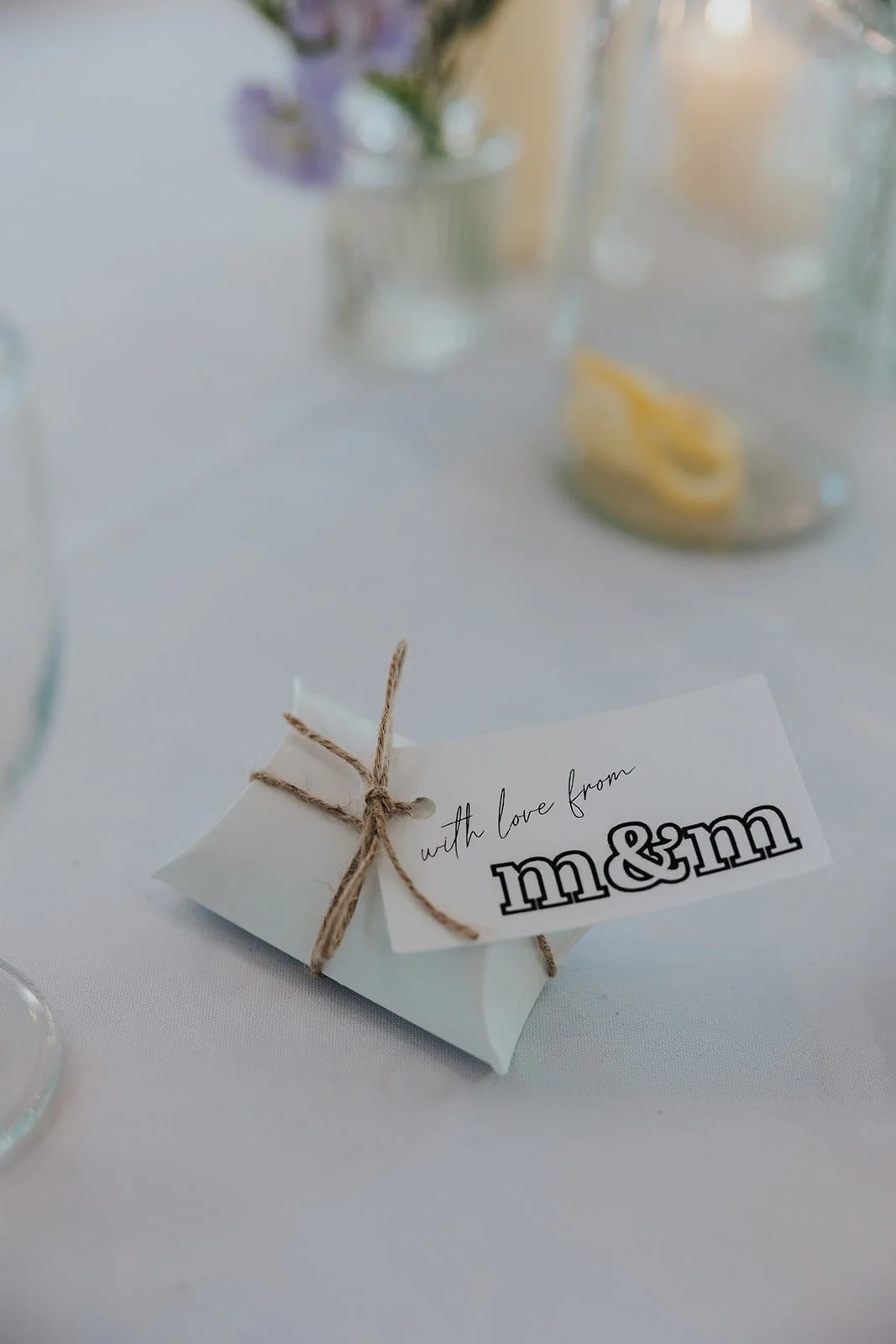 closeup of wedding favor box with paper that says "with love from m&m" with M&Ms inside