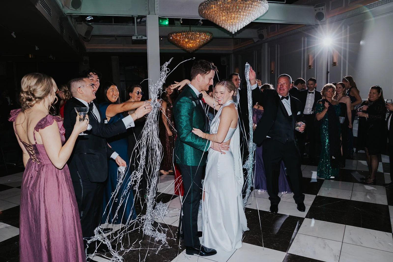 bride and groom laughing while wedding guests throw streamers for New Year's Eve at wedding reception in Chicago