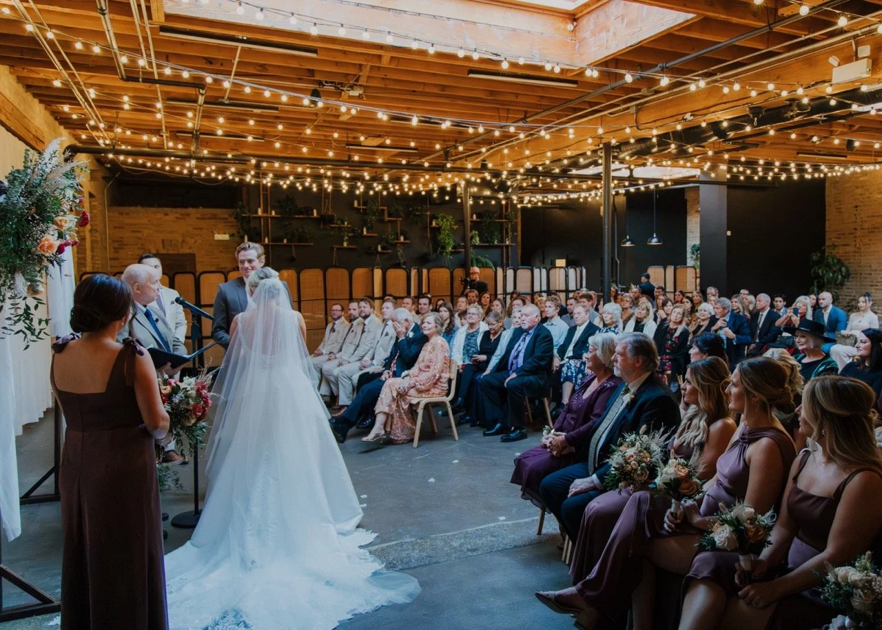 wedding ceremony guests focus with string lights shining and natural sky light in The Arbory