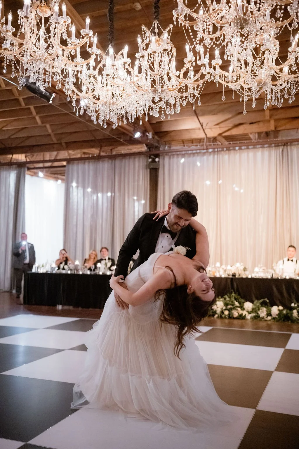 Bride and groom first dance dip on black and white checkered dance floor
