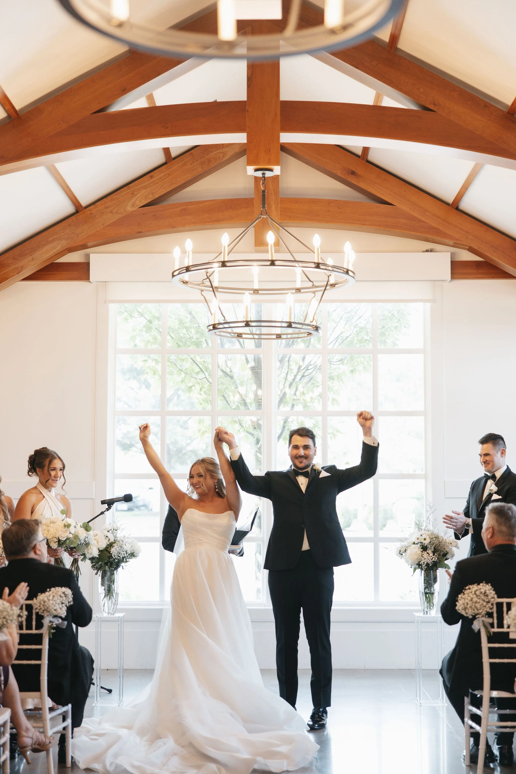 Bride and groom holding each other's hands up and cheering after just getting married