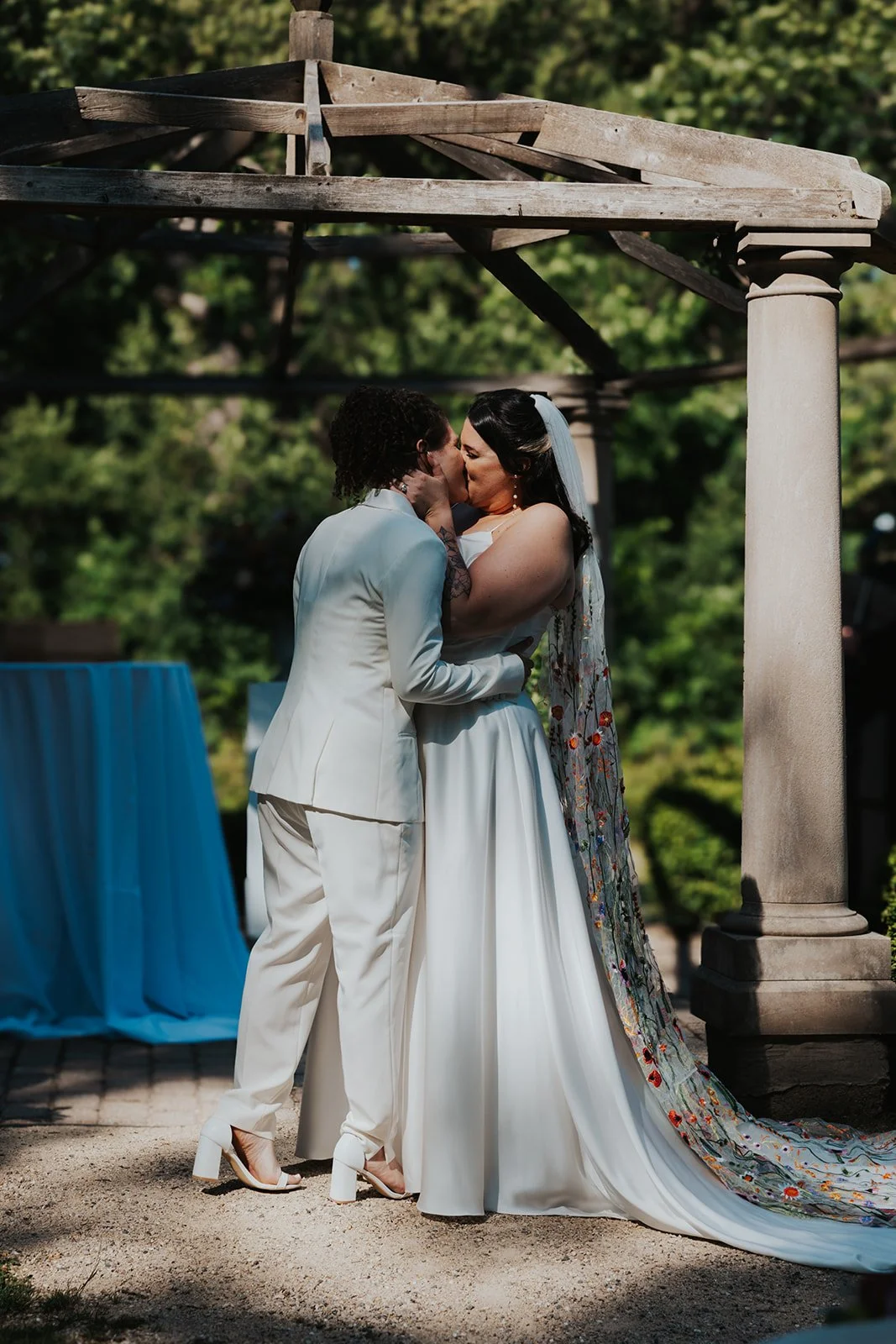 Two brides' first kiss at wedding ceremony under a gazebo