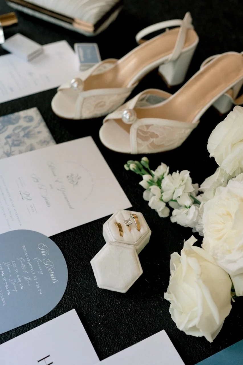 invitation suite flatlay with flowers, rings, and shoes