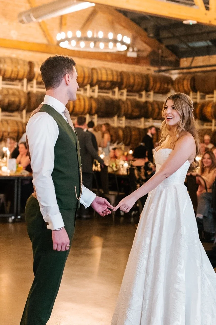Couple touching fingertips and smiling on dance floor for first dance at Goose Island Barrel House