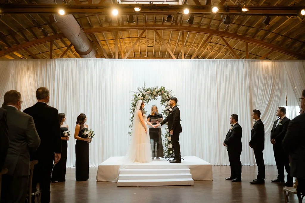 bride and groom standing on stage holding hands during wedding ceremony