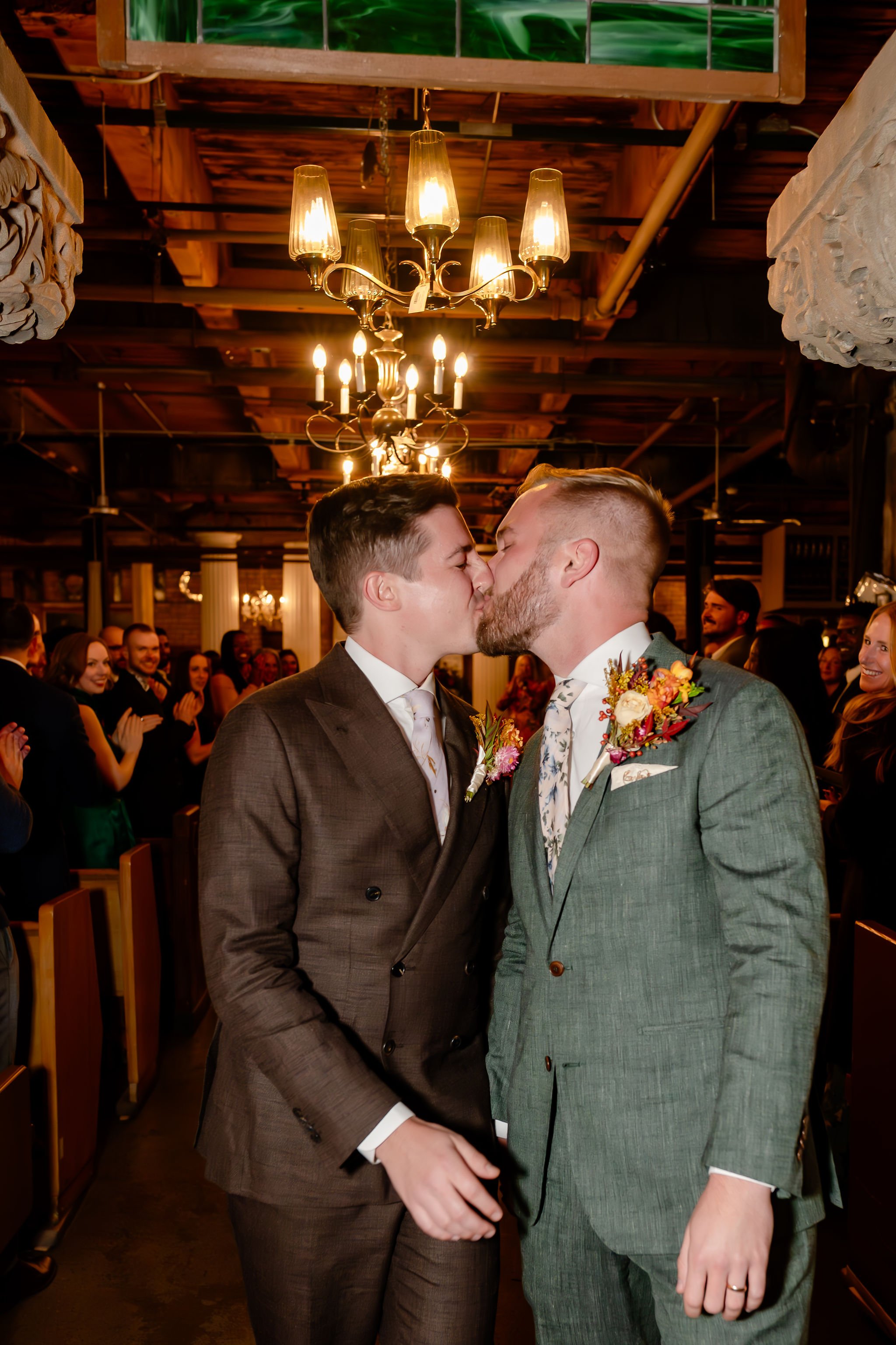 Two grooms closeup of kiss after ceremony just married recessional kiss down the aisle