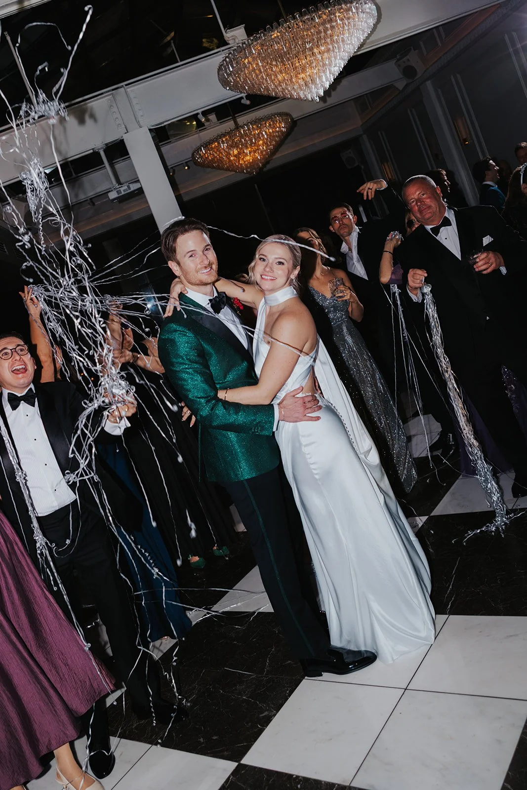 couple smiling at camera on dance floor new year's eve streamers thrown